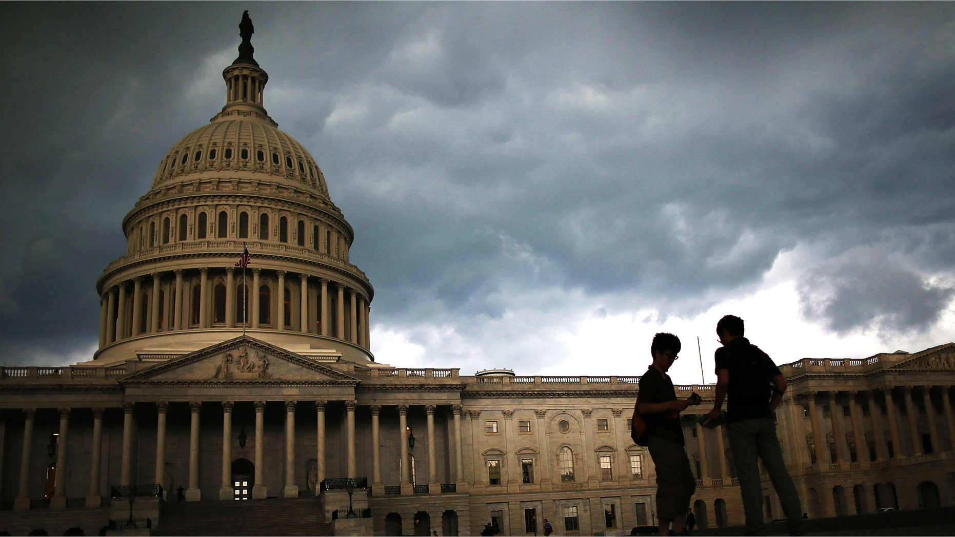 WASHINGTON, DC - JUNE 13: Two men stand on the plaza of the U.S. Capitol Building as storm clouds fill the sky, June 13, 2013 in Washington, DC. Potentially damaging storms are forecasted to hit parts of the east coast with potential for causing power wide spread outages. (Photo by Mark Wilson/Getty Images)