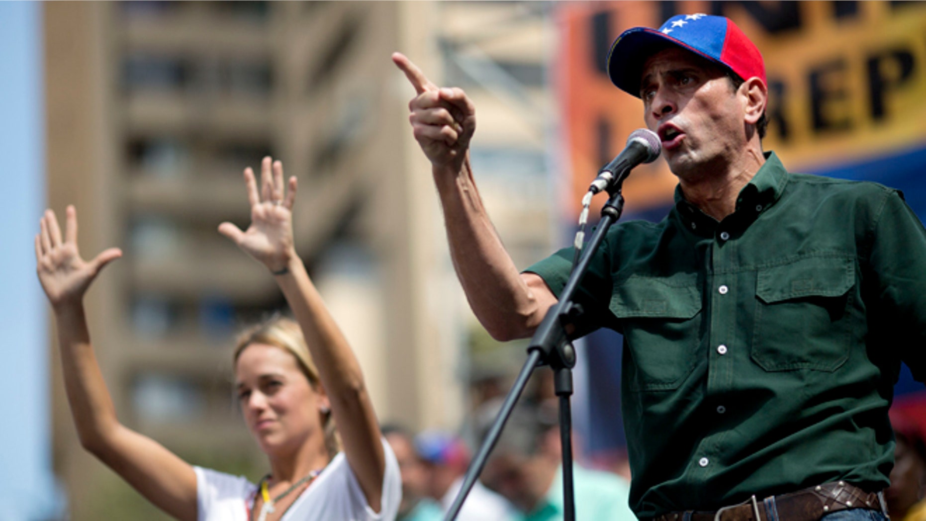 Opposition leader Enrique Capriles delivers a speech next to Lilian Tintori, wife of detained opposition leader Leopoldo Lopez, during a rally in Caracas, Venezuela, Saturday, Feb. 22, 2014. Authorities blamed opposition leader Lopez for fomenting he violence and jailed him on charges including arson and incitement, prompting anger from his supporters at home and criticism from abroad. Supporters and opponents of the government of President Nicolas Maduro are holding competing rallies in the bitterly divided country. (AP Photo/Rodrigo Abd)