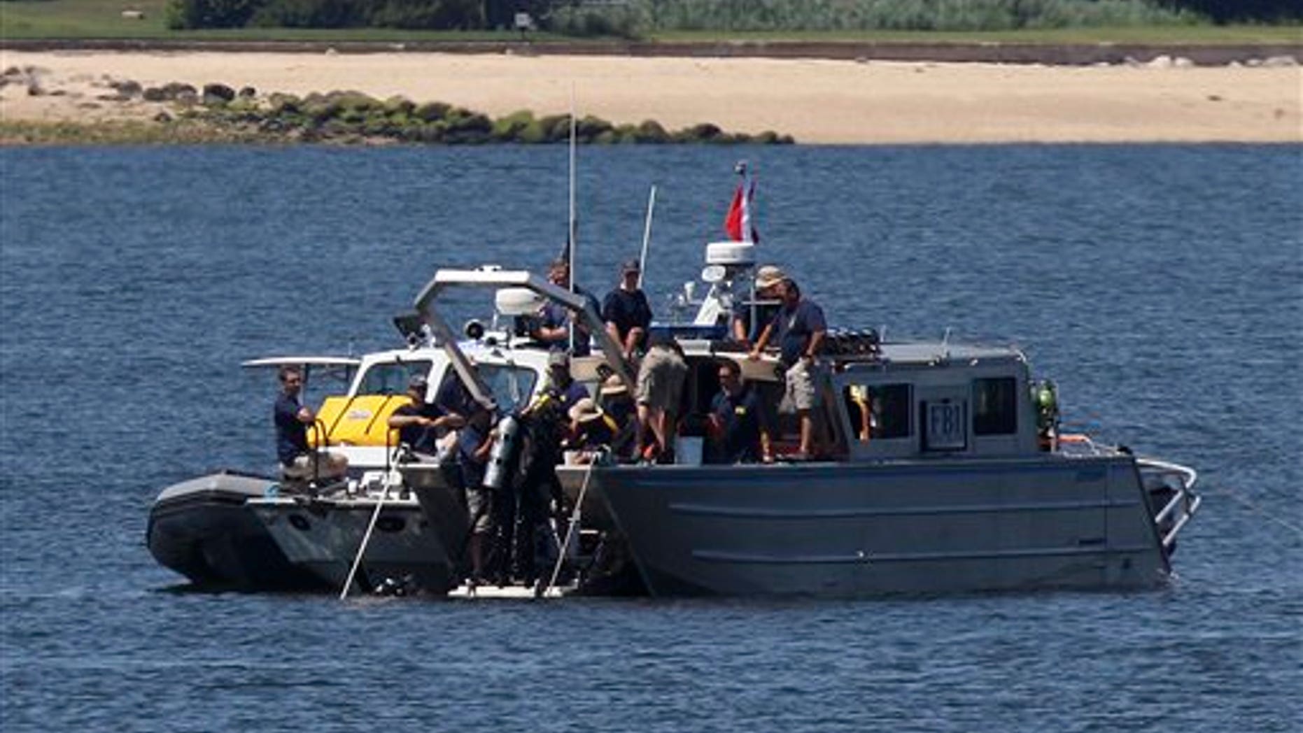 July 10, 2012: Divers leave the water and come up onto an FBI boat over the site of a sunken yacht near Lloyd Harbor, N.Y.