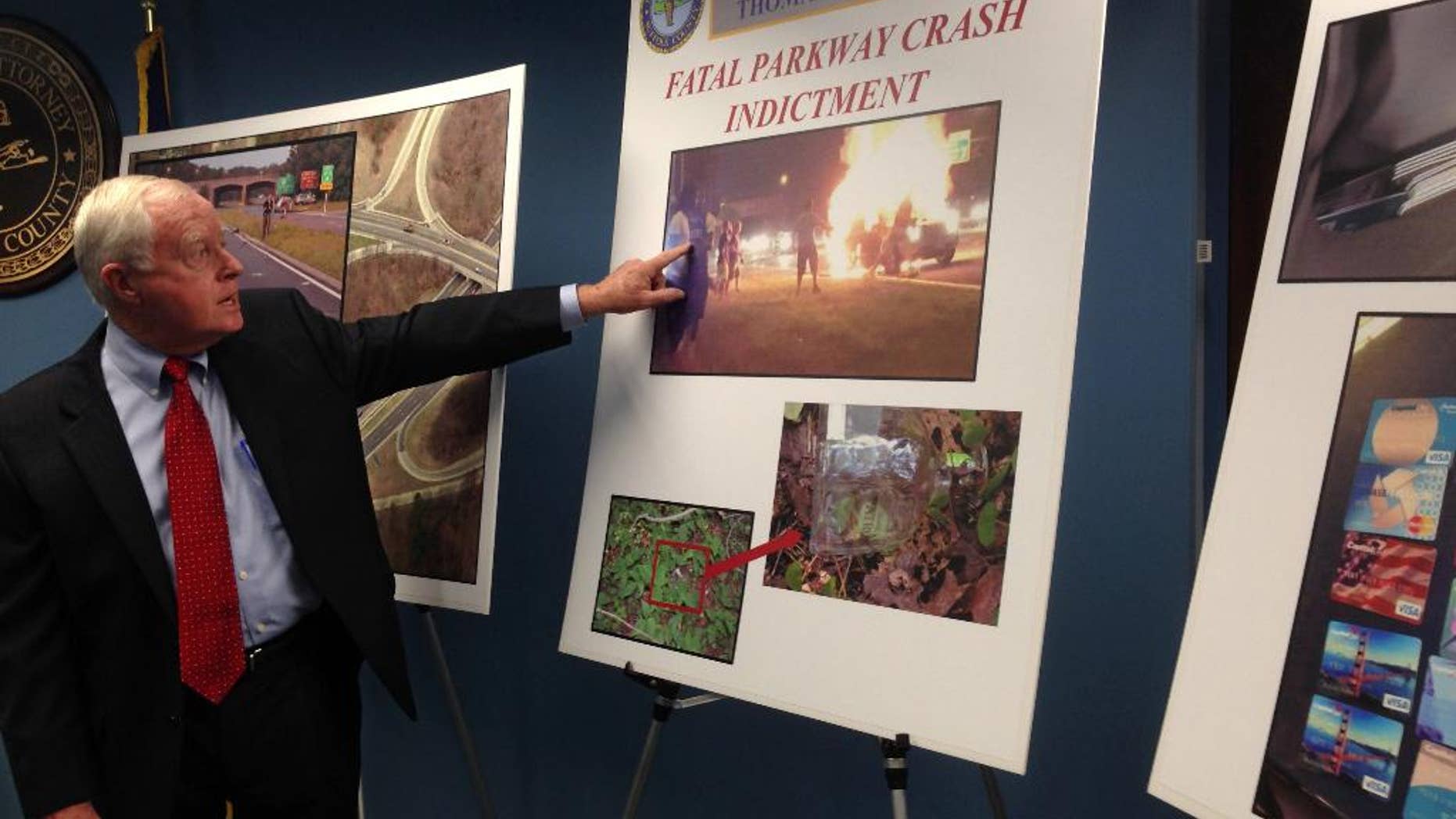 Suffolk County District Attorney Thomas J. Spota points to a photograph of the aftermath of a July 12, 2015, car crash on the Southern State Parkway that killed a father and his two children, Thursday, Aug. 27, 2015 in Hauppauge, N.Y. The prosecutor announced criminal charges Thursday against four people allegedly involved in the crash. All four have pleaded not guilty. (AP Photo/Frank Eltman)