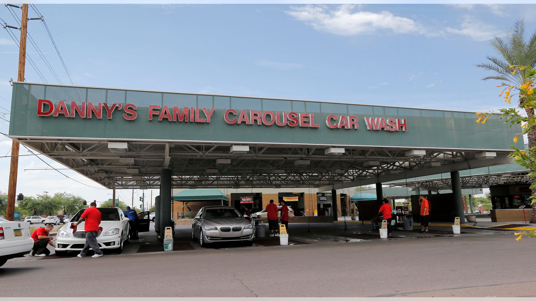 Employees at Danny's Family Car Wash wipe down cars, Monday, Aug. 19, 2013 in Phoenix. Authorities are expected to unseal indictments Monday from a two-year investigation of a metro Phoenix car wash business and its human resource provider, revealing the company leaders who were arrested in a raid and detailing the allegations against them. (AP Photo/Matt York)