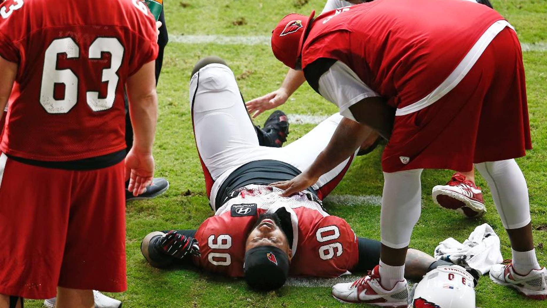 Arizona Cardinals defensive end Darnell Dockett is atended while down in pain during NFL football training camp Monday, Aug. 18, 2014 at University of Phoenix Stadium in Glendale, Ariz. Dockett left the field on a cart. (Photo by Rob Schumacher/The Arizona Republic) (AP Photo/The Arizona Republic, Rob Schumacher) MARICOPA COUNTY OUT; MAGS OUT; NO SALES