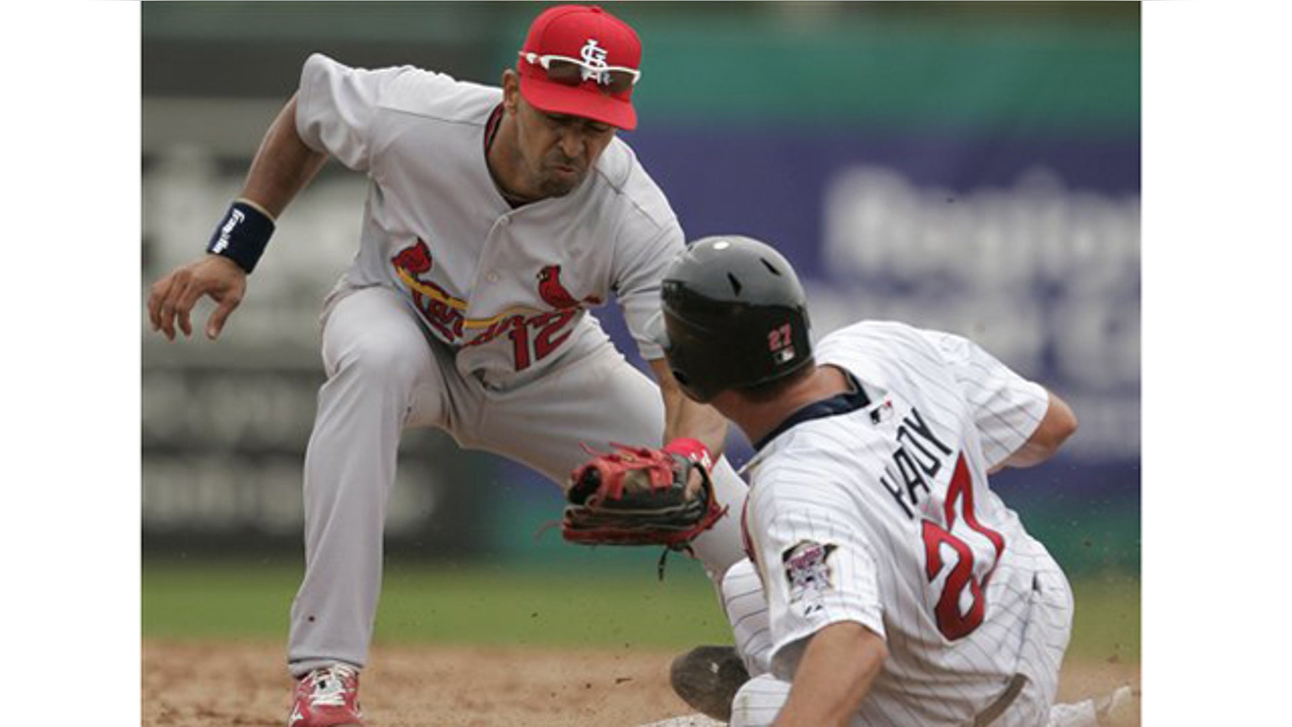St. Louis Cardinals shortstop Julio Lugo tries to tag Minnesota Twins' J.J. Hardy who steals second base in the second inning of a spring training baseball game in Fort Myers, Fla., Tuesday, March 9, 2010.