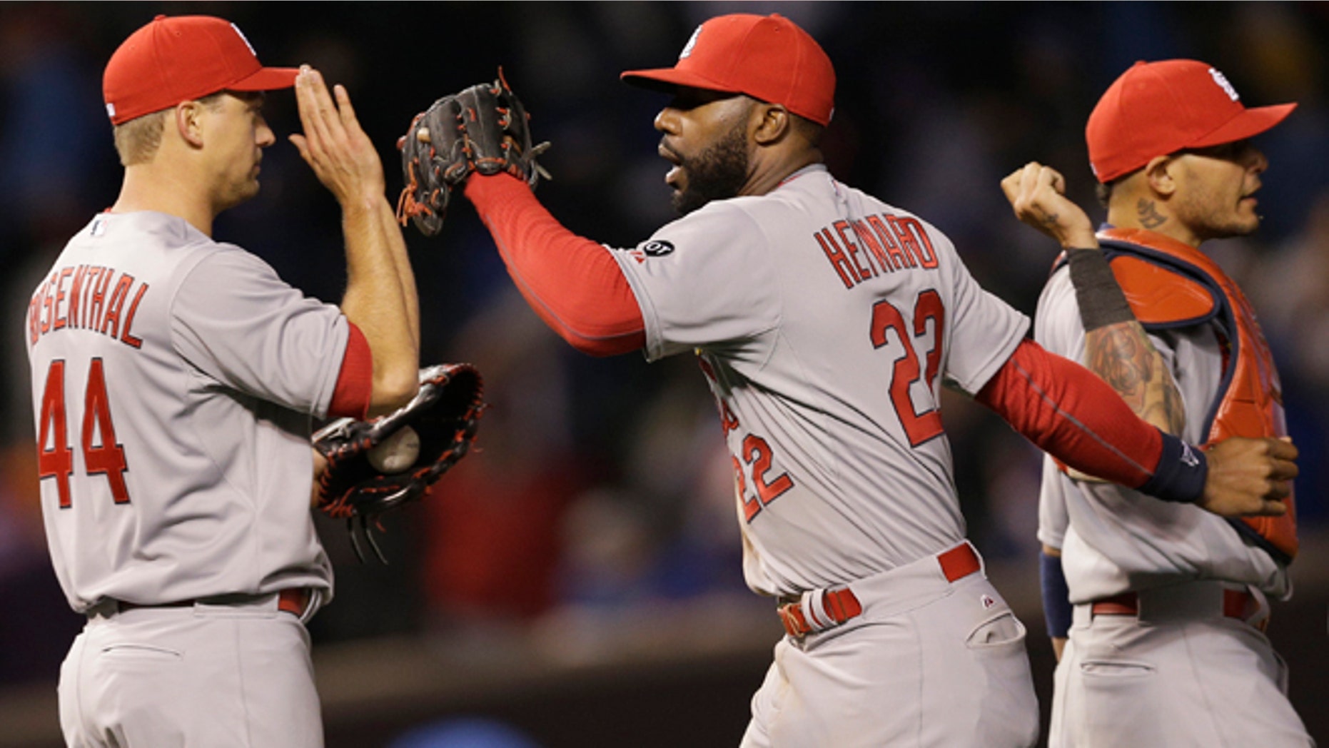 St. Louis Cardinals right fielder Jason Hayward, center, celebrates with closer Trevor Rosenthal, left, and catcher Yadier Molina after the St. Louis Cardinals defeated the Chicago Cubs 3-0 in a Major League Baseball season-opening game in Chicago, Sunday, April 5, 2015. (AP Photo/Nam Y. Huh)
