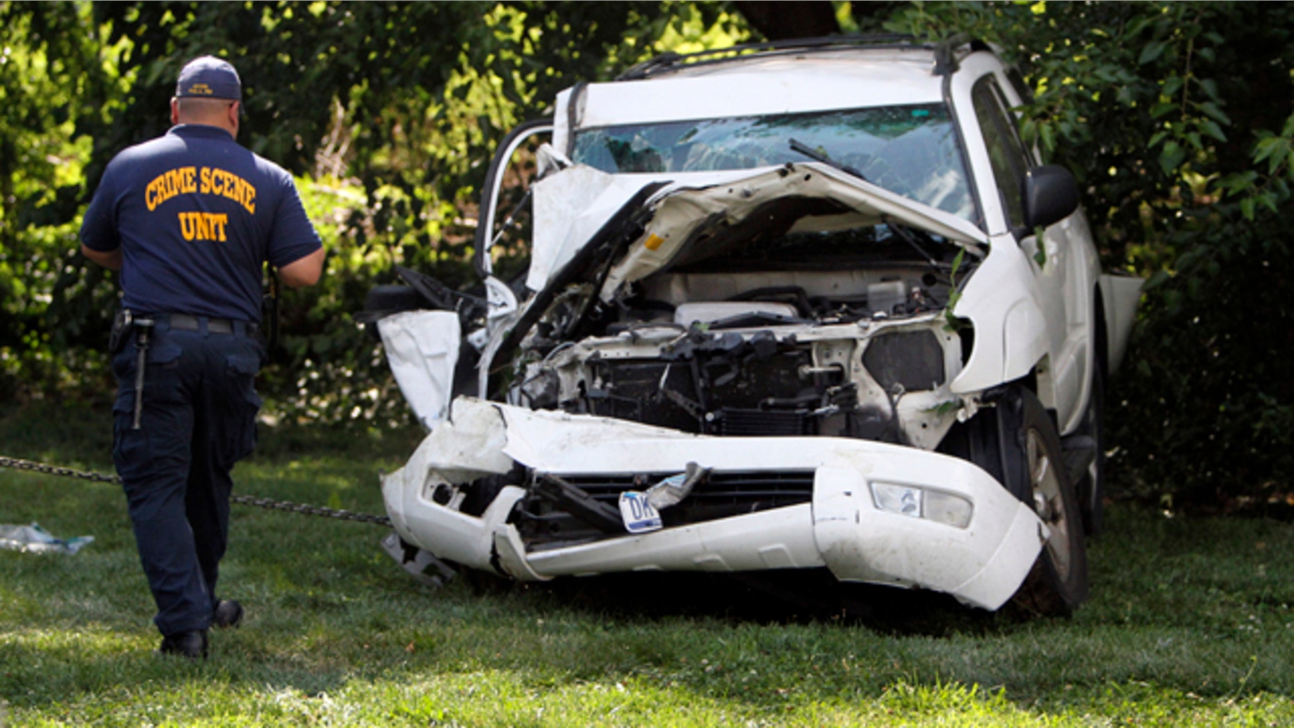 July 25, 2014: An investigator examines a heavily damaged SUV before it is towed from the scene of a fatal accident in North Philadelphia. Two children were killed and three people critically injured when a hijacked car lost control and hit a group of people near a fruit stand, according to police. (AP Photo/ Joseph Kaczmarek)