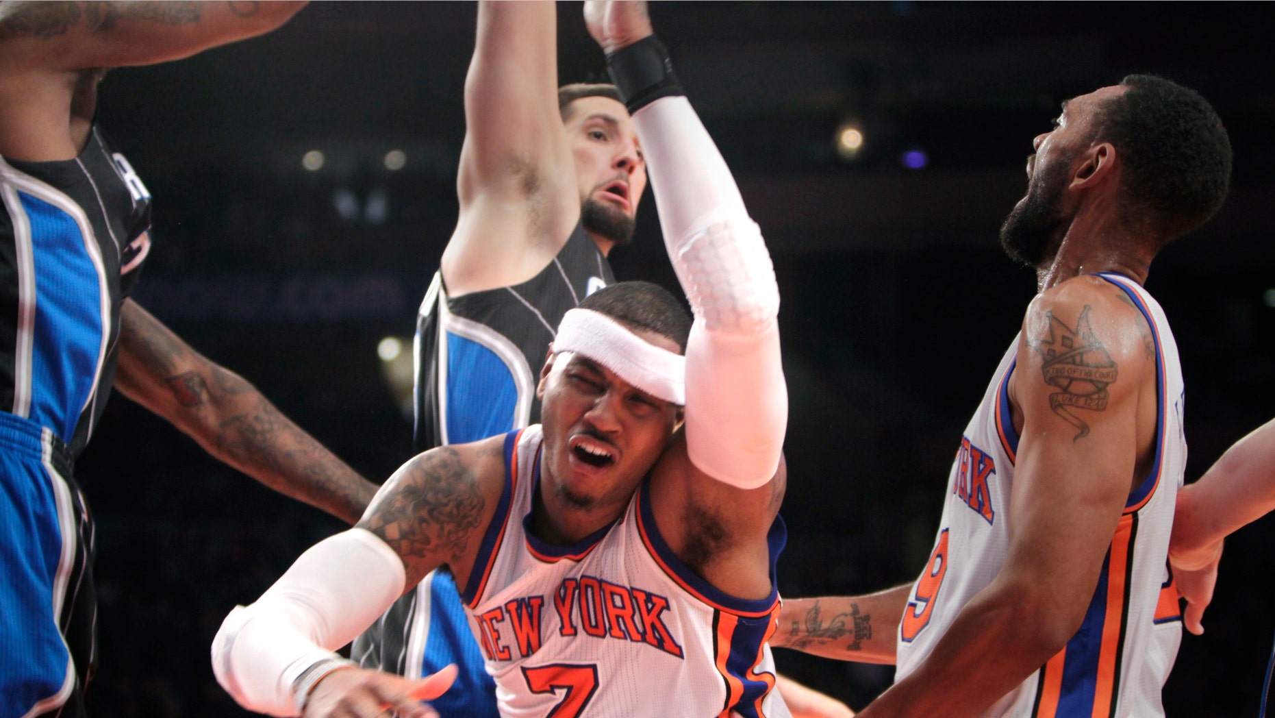 New York Knicks' Carmelo Anthony, center, is knocked down while going for a basket during the first half of an NBA basketball game in New York, Monday, Jan. 16, 2012. (AP Photo/Seth Wenig)