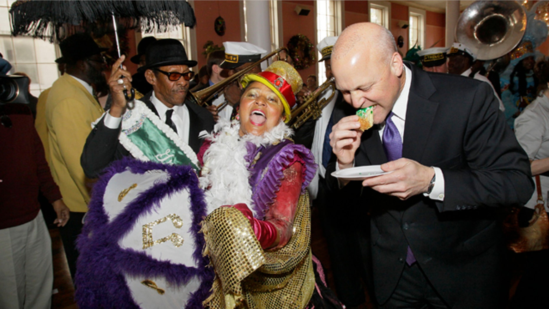 New Orleans Mayor Mitch Landrieu, right, takes a bite of traditional Mardi Gras king cake as a second line parade passes by during a ceremony to mark the beginning of carnival season in New Orleans, Thursday, Jan. 6, 2011. (AP Photo/Patrick Semansky)