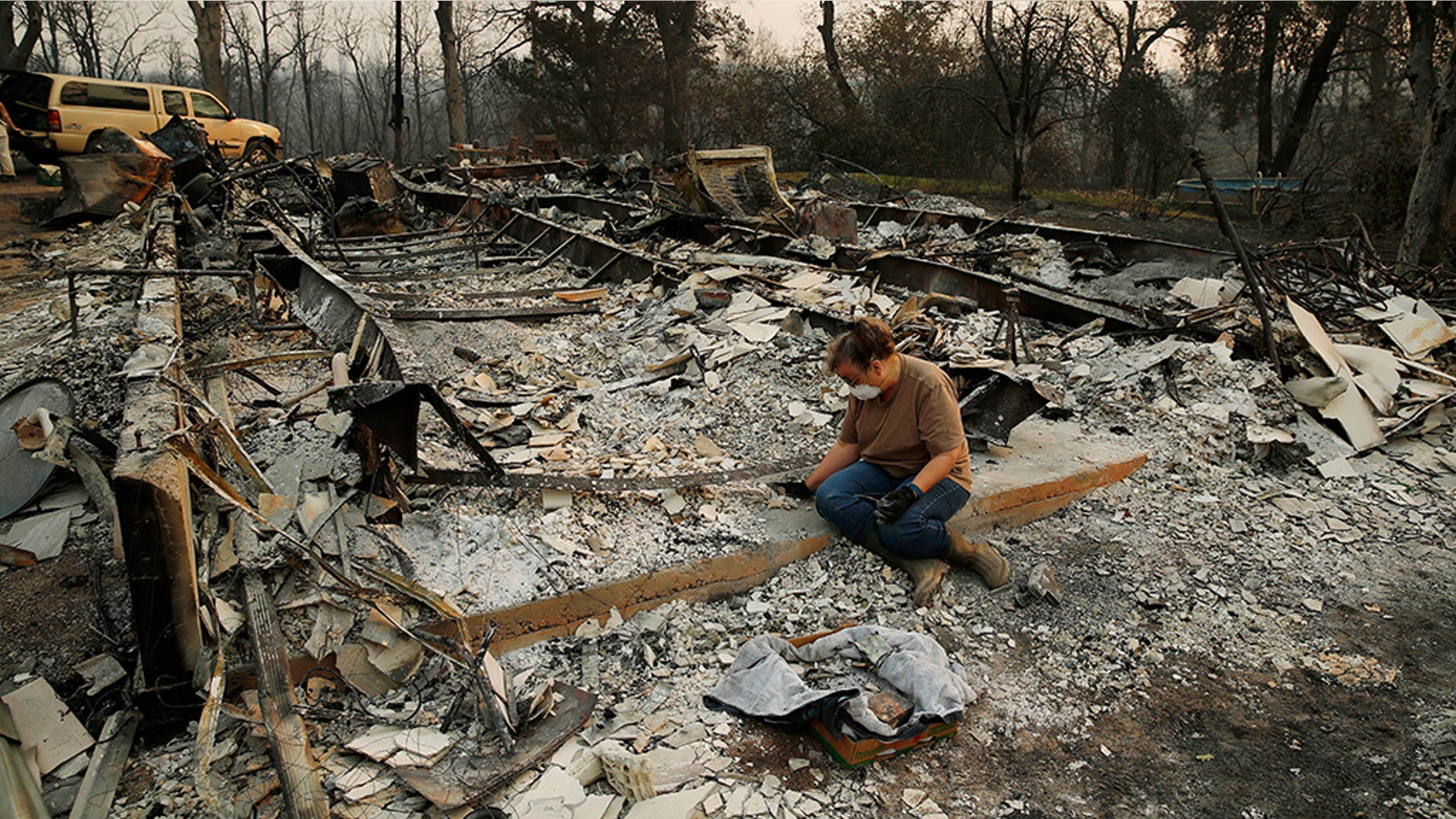 Kim Burns sifting through the charred rubble of her home burned in the Carr Fire, Sunday, Aug. 12, 2018, in Redding, Calif.