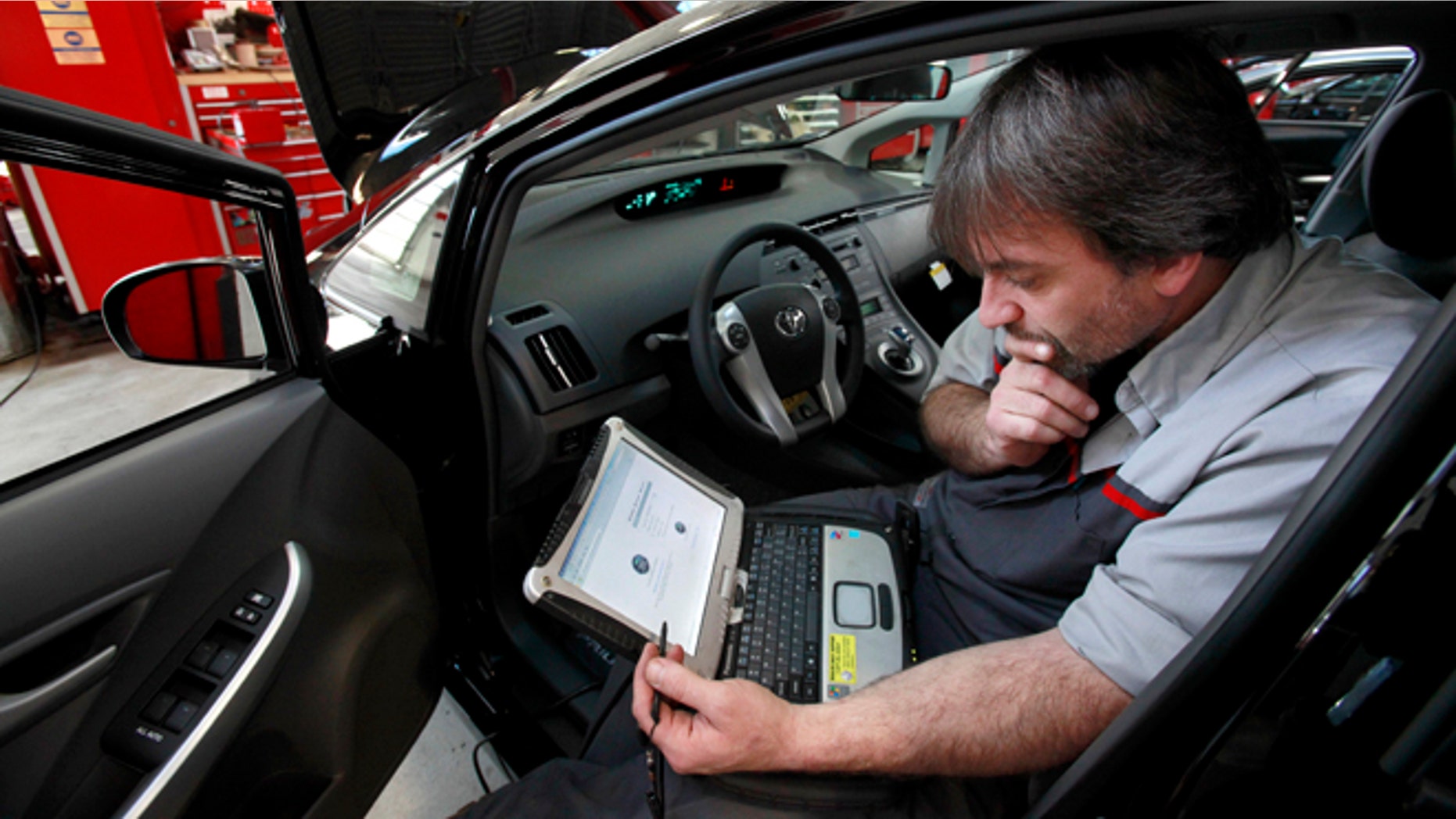 FILE - In this Feb. 9, 2010 file photo, master diagnostic technician Kurt Juergens, of Foxborough, Mass., uses a laptop computer to diagnose and repair the brake system on a 2010 Toyota Prius in the repair shop of a Toyota dealership, in Norwood, Mass. A pair of hackers maneuvered their way into the computer systems of a 2010 Toyota Prius and 2010 Ford Escape through a port used by mechanics. The hackers showed that they could slam on the brakes at freeway speeds, jerk the steering wheel or even shut down the engine, all from their laptop computers. The work demonstrates vulnerabilities with the growing number of car computers, about 20 on older models and up to 70 on sophisticated luxury cars. (AP Photo/Steven Senne, File)