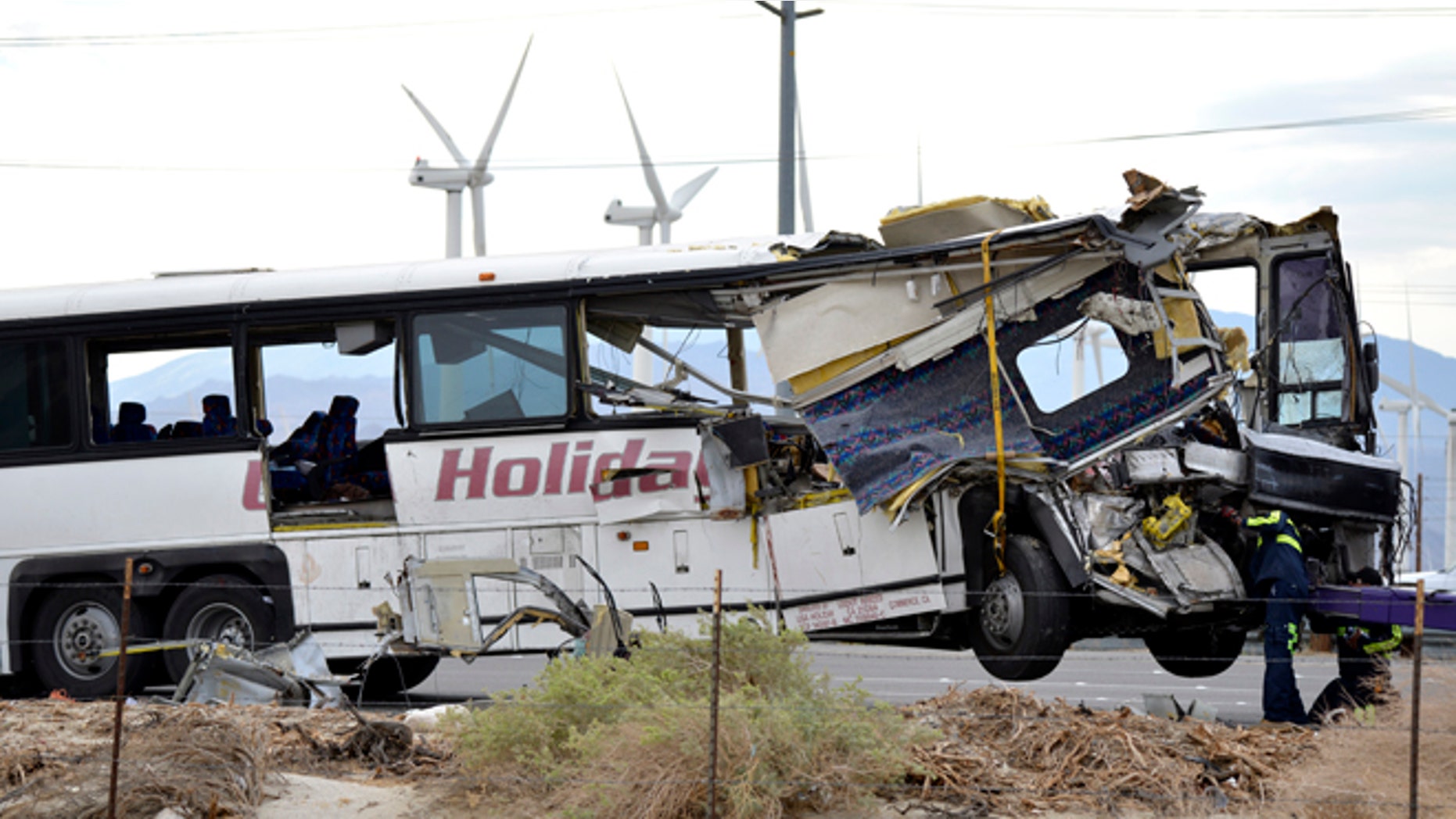Workers prepare to haul away a tour bus that crashed with semi-truck on Interstate 10 just west of the Indian Canyon Drive off-ramp, in Desert Hot Springs, near Palm Springs, Calif., Sunday, Oct. 23, 2016. The tour bus and a semi-truck crashed on the highway in Southern California early Sunday, killing at least a dozen of people and injuring at least 30 others, some critically, the California Highway Patrol said. (AP Photo/Rodrigo Pena)