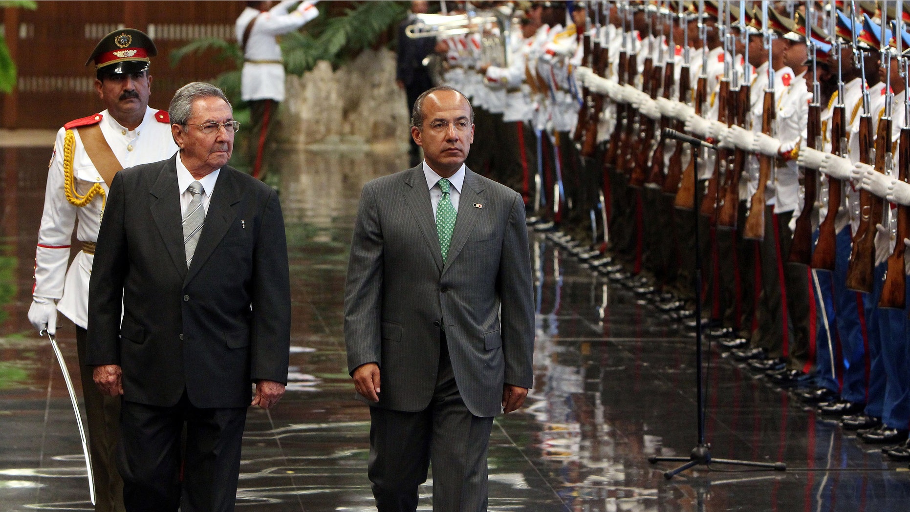 Cuba's President Raul Castro, front left, and Mexico's President Felipe Calderon review a honor guard during a ceremony at the Revolution palace in Havana, Cuba, Wednesday, April 11, 2012. Calderon is on a two-day official visit to Cuba. (AP Photo/Alejandro Ernesto, Pool)
