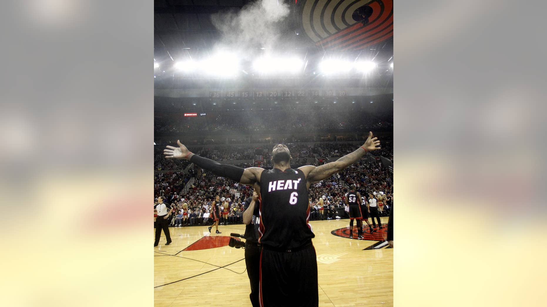 FILE - In this March 1, 2012 file photo, Miami Heat's LeBron James (6) throws powder in the air at the start of their NBA basketball game with the Portland Trail Blazers, in Portland, Ore. There was no eye contact, nothing to indicate any reconciliation. The breakup of LeBron James and Cavaliers owner Dan Gilbert was beyond bitter. But now, as James considers a return to the team he abandoned four years ago with an entire region breathlessly awaiting a homecoming it couldn't imagine in its wildest dreams, it appears there has been some healing between the NBA superstar and his former boss. (AP Photo/Rick Bowmer, File)