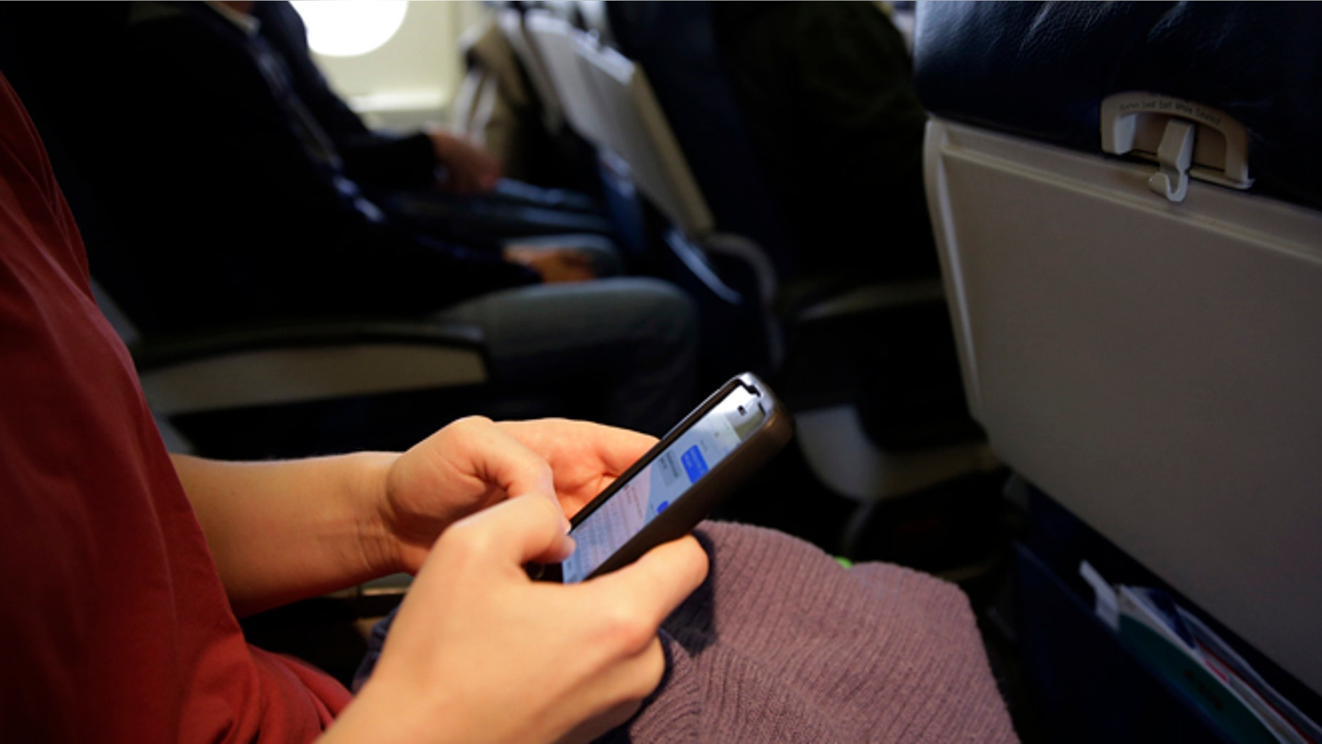Oct. 31, 2013 A passenger checks her cell phone before a flight in Boston.