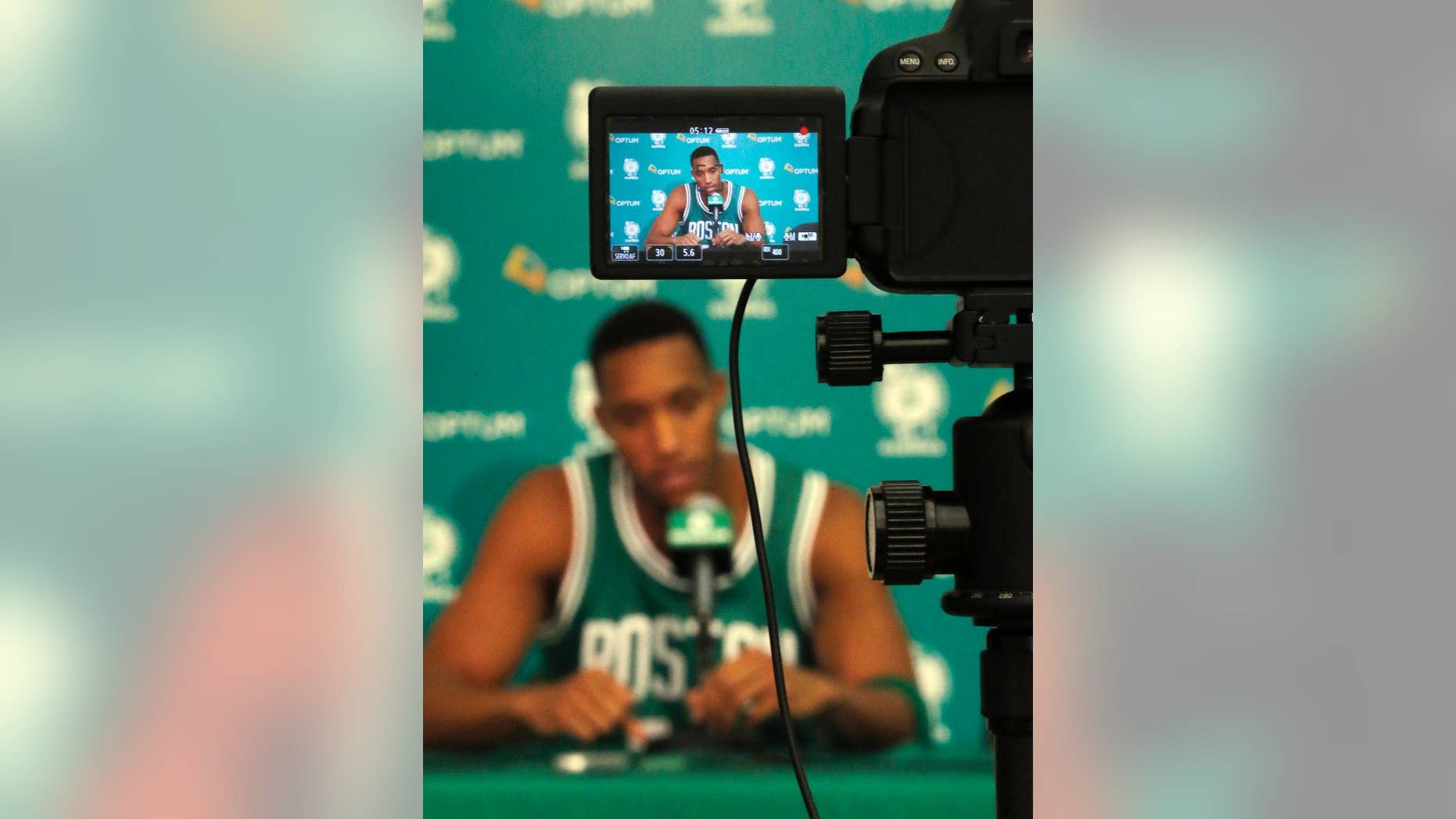 Boston Celtics guard Evan Turner, displayed on the screen of a video camara, speaks to reporters during NBA basketball media day in Waltham, Mass., Monday, Sept. 29, 2014. (AP Photo/Elise Amendola)