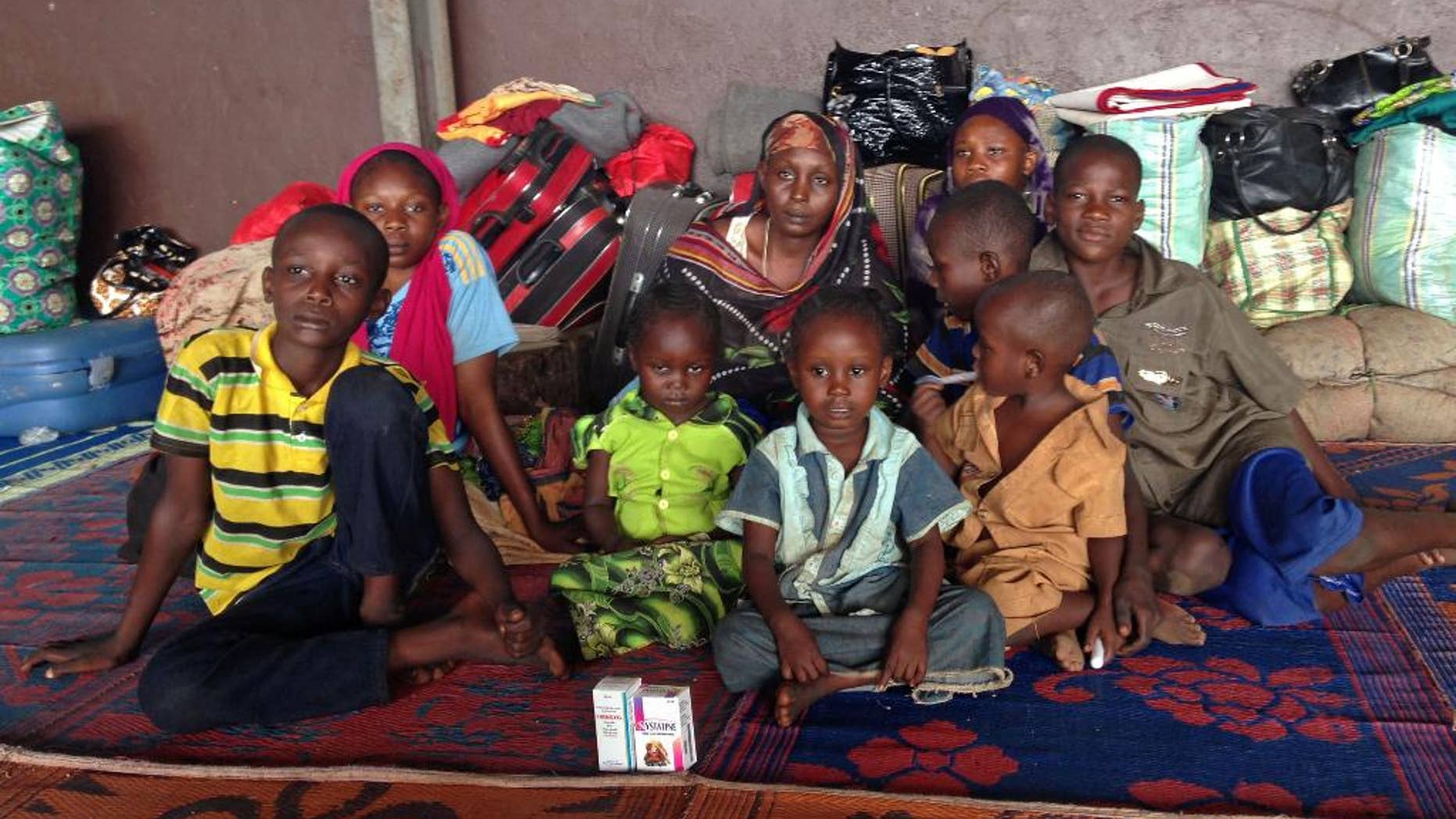 In this photo taken on Friday March 7, 2014, Yaman Ahmat, center, sits with her children at Bangui Airport after only hours earlier, her husband Marcus Madi, had put her and their eight children including newborn daughter Ashta onto a flight to the capital in a desperate bid to save their lives, but he was tragically killed on his return from the airport. The two married when they were 17-year old and now have a large family, but Marcus Madi had to return to sell what remained of his store merchandise before leaving to join his family in safety, but he died in a hail of gunfire, leaving his family with their belongings packed into the bags behind them at the airport. (AP Photo/Krista Larson)