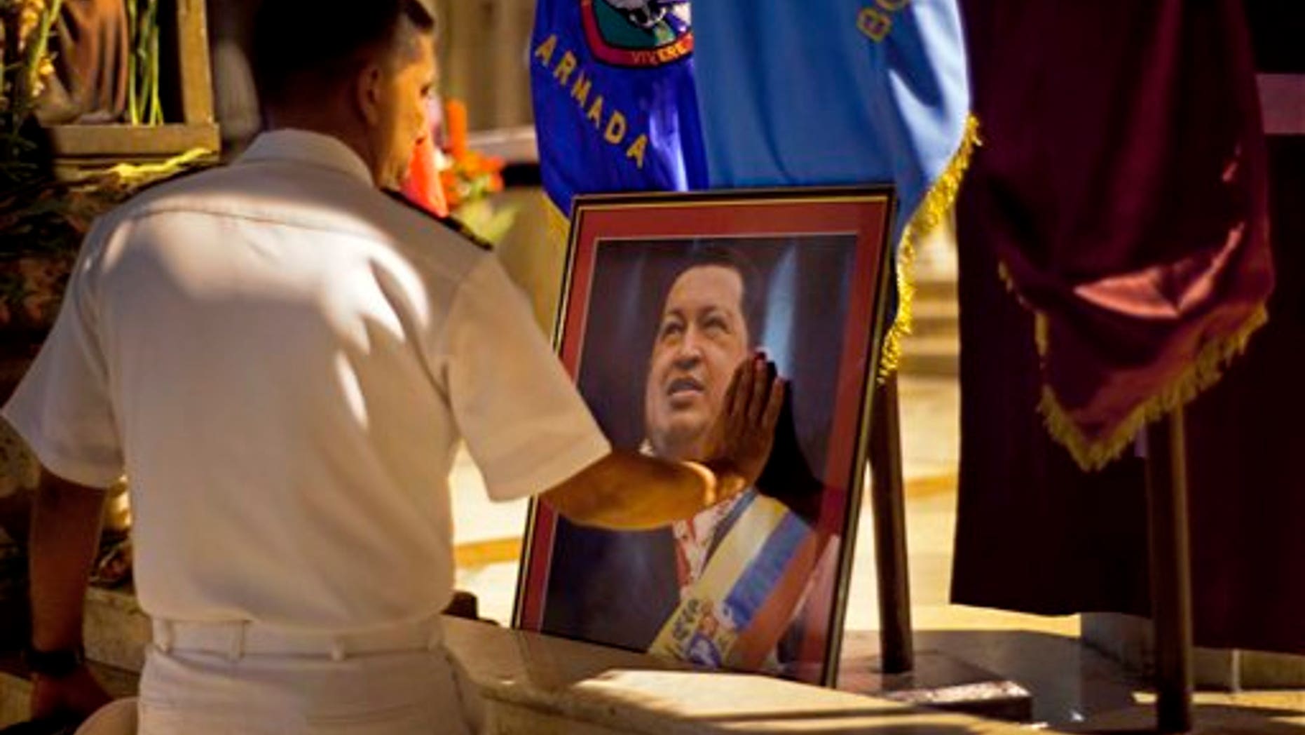 A member of Venezuela's navy touches an image of President Hugo Chavez after a mass in support of him in Havana, Cuba.