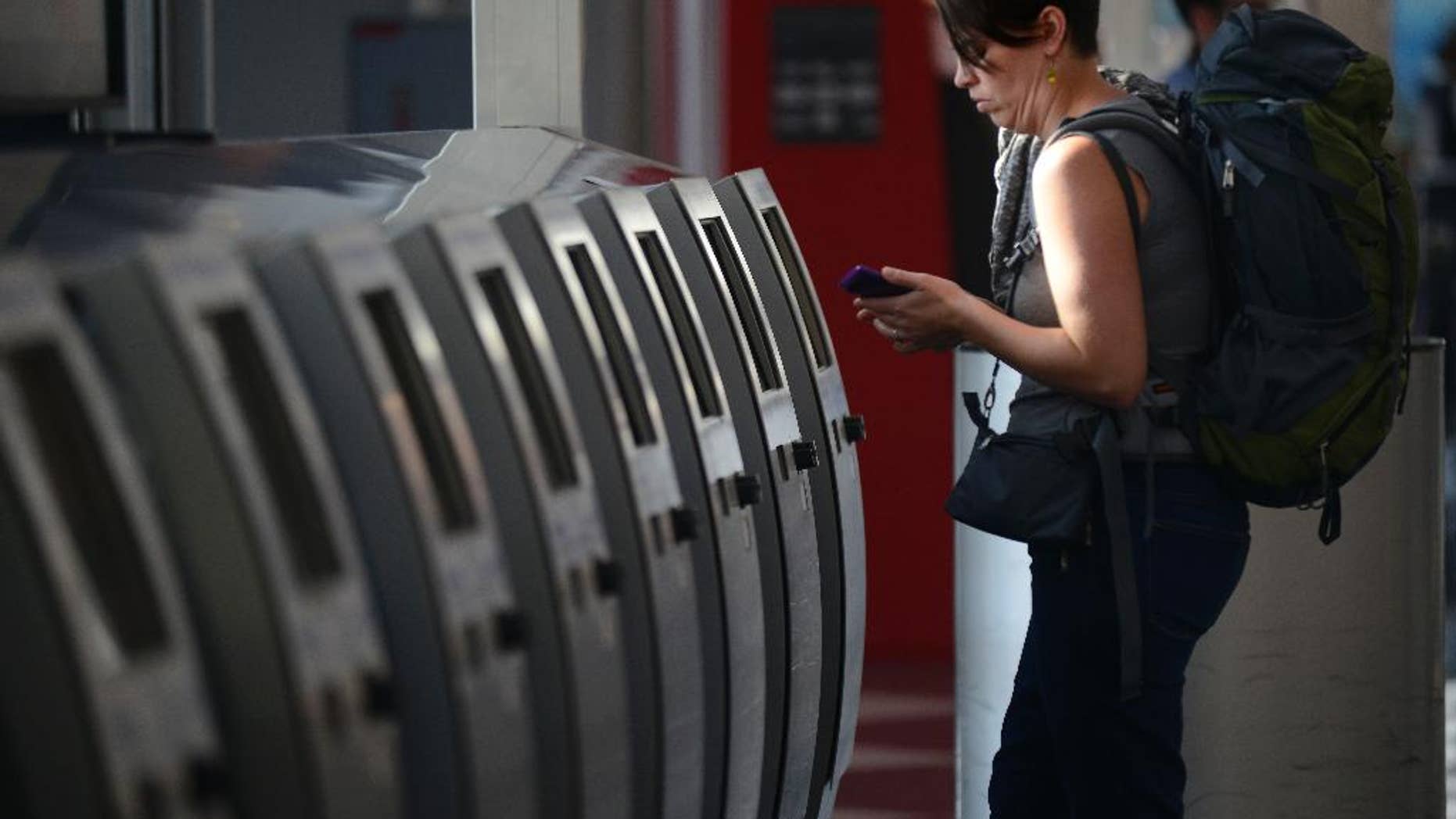 Breanne Eging checks on her flight to Greenville, South Carolina at O'Hare International Airport in Chicago, Friday, Sept. 26, 2014. All flights in and out of Chicago's two airports were halted Friday after a fire at a suburban air traffic control facility sent delays and cancellations rippling through the U.S. air travel network. Authorities said the blaze was intentionally set by a contract employee of the Federal Aviation Administration and had no ties to terrorism. (AP Photo/Paul Beaty)