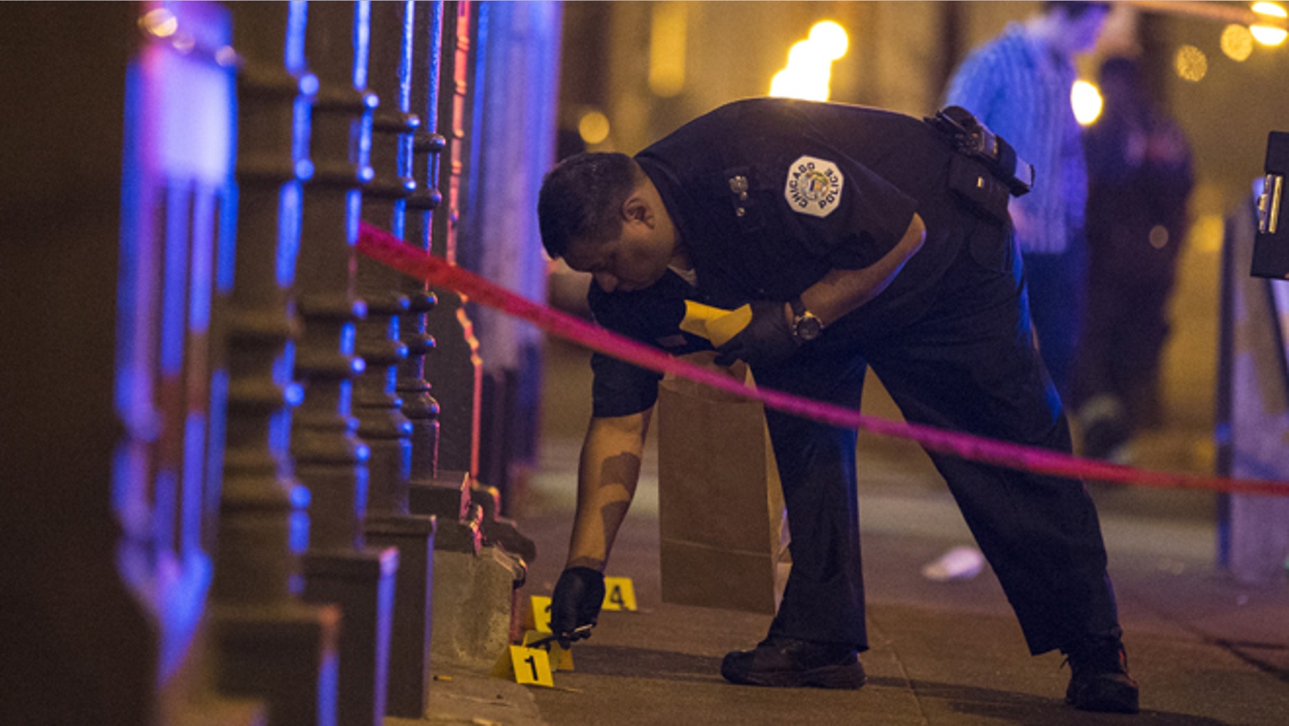 July 5, 2015: A Chicago police officer collects evidence at a crime scene where a man was shot in the city.