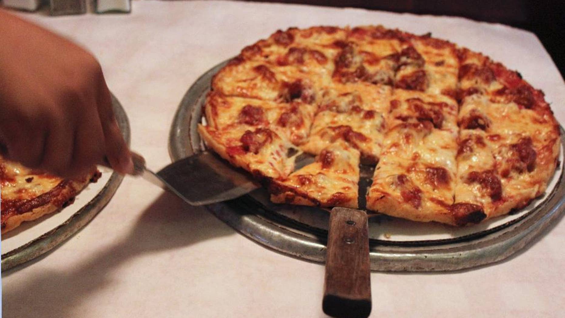 Sept. 5, 2014l A waitress serves a cheese and sausage pizza to participants on a pizza tour at Pizano's in Chicago.