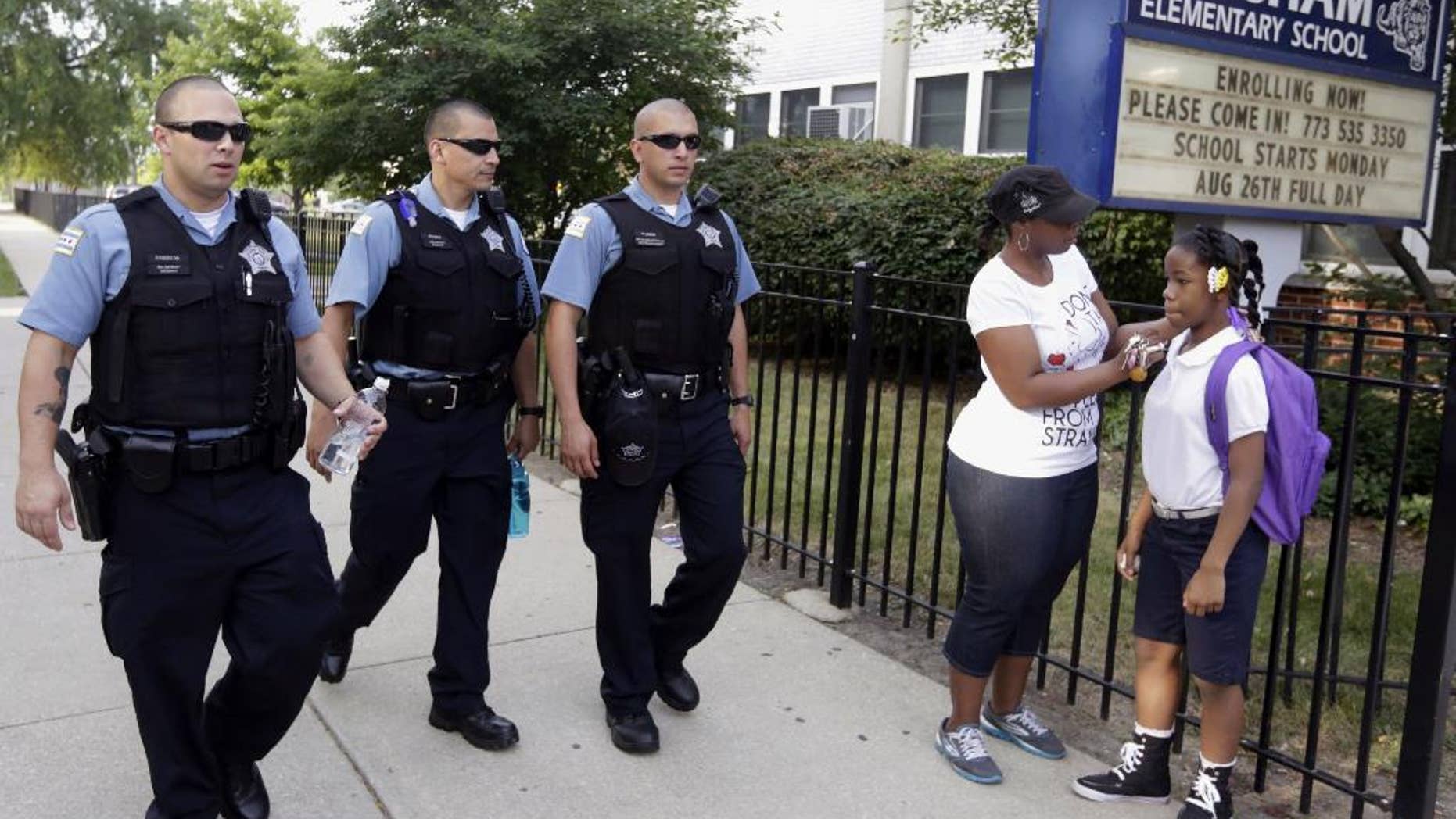 FILE - In this Aug. 26. 2013, file photo, Chicago Police patrol the neighborhood at Gresham Elementary School on the first day of classes in Chicago. Thanks to $1 million from the city, another 100 “Safe Passage” workers will be on routes kids walk through crime-ridden neighborhoods when classes resume Tuesday, Sept. 2, 2014. (AP Photos/M. Spencer Green, File)