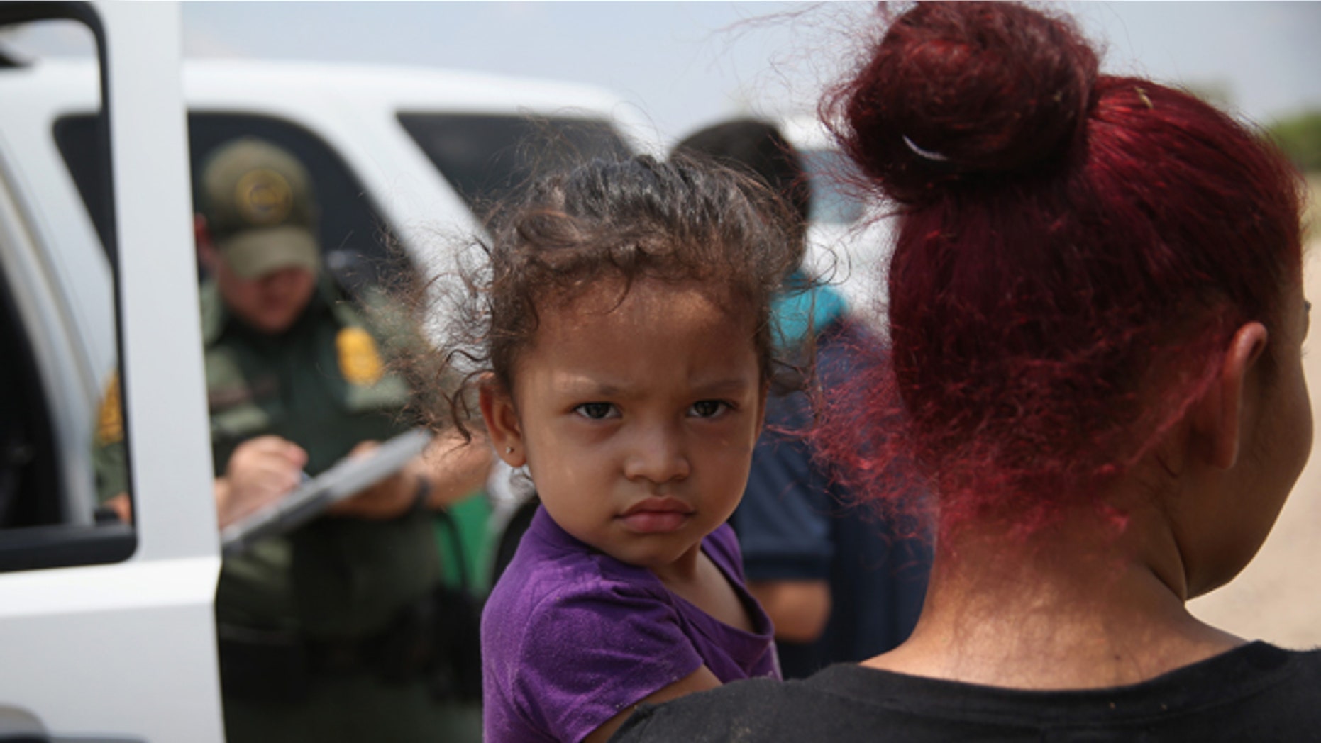 A mother and child, 3, from El Salvador await transport to a processing center for undocumented immigrants after they crossed the Rio Grande into the United States on July 24, 2014 in Mission, Texas. (Photo by John Moore/Getty Images)