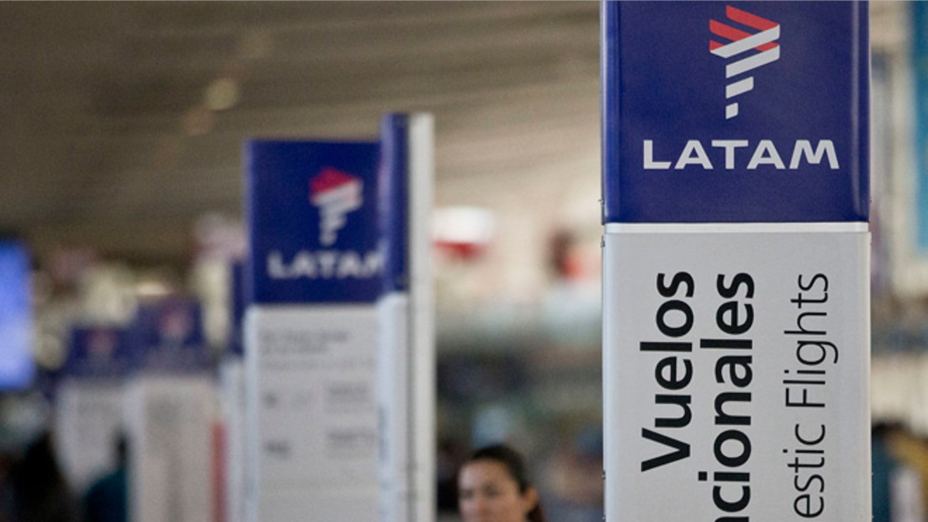 An agent of LATAM airlines stands by the counters at the airport in Santiago, Chile, Monday, July 25, 2016. LATAM airlines created in 2012 after a fusion between the airlines LAN of Chile and TAM of Brazil, has agreed to pay more than $22 million in fines related with a scheme to bribe Argentine union officials via a false consulting contract. The airline will pay the fine to the Securities and Exchange Commission (SEC) and the Department of Justice (DOJ) for a violation of the accounting provisions of the Foreign Corrupt Practices Act. (AP Photo/Esteban Felix)