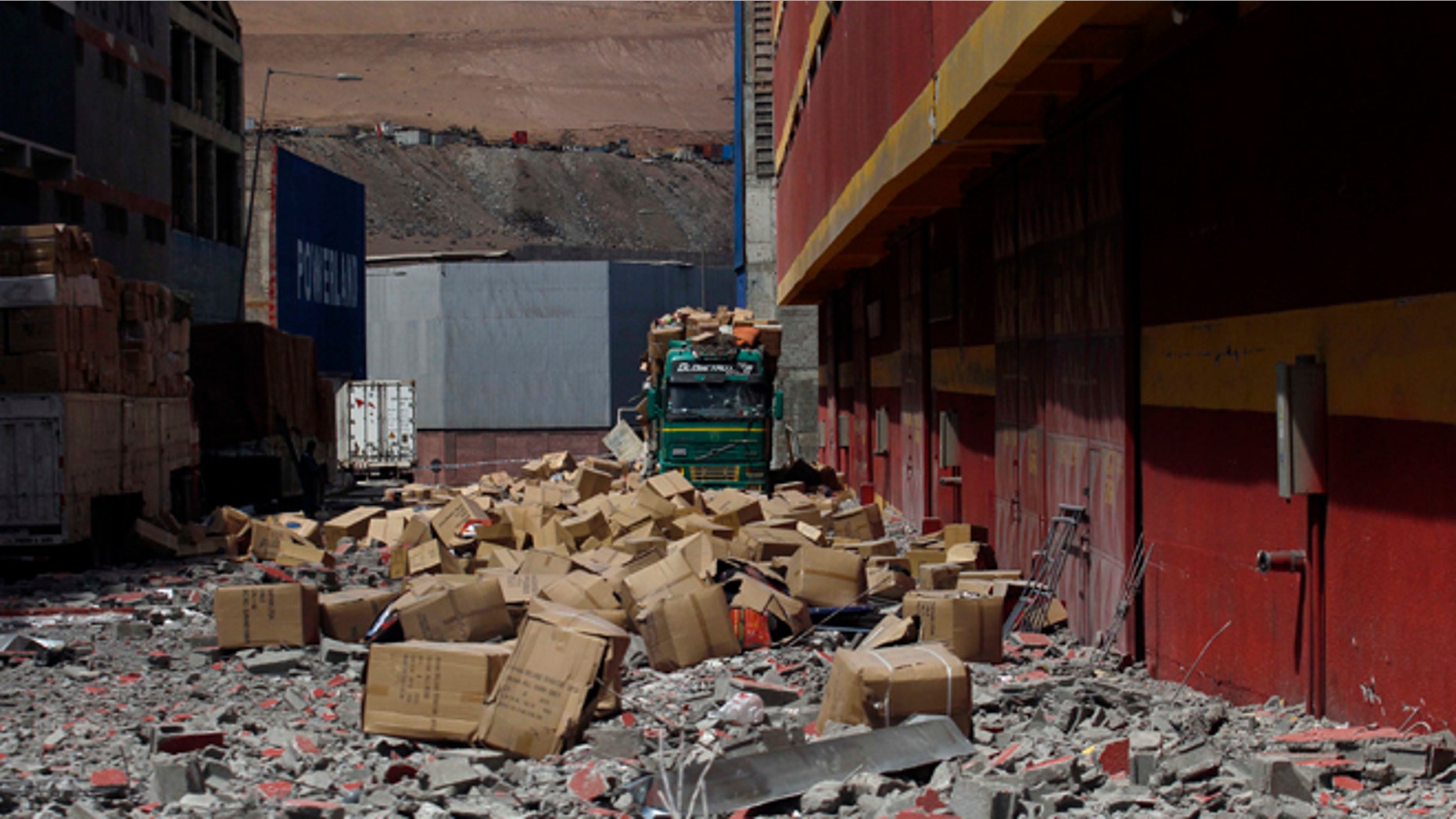 A truck remains covered by debris and boxes of fallen merchandise that fell from the earthquake ravaged Duty Free Zone of Iquique, in Iquique, Chile, Friday, April 4, 2014. Following a magnitude-8.2 earthquake early in the week, soldiers have kept a close watch on supermarkets and gas stations to prevent looting as many people continued to line up on Friday for gasoline, water and food. The city remained largely peaceful and no new major damage or casualties were reported from the continuing aftershocks that have rattled the sleep-deprived citizens of Chile's north. (AP Photo/Luis Hidalgo)