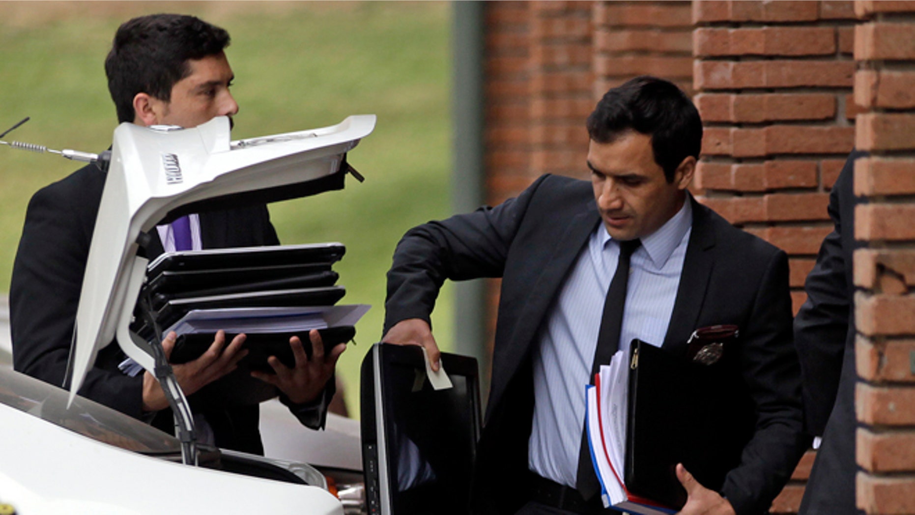Police investigators carry documents and computers taken from the office of Chile's former president of the National Association of Professional Soccer, ANFP, Sergio Jadue, in Santiago, Chile, Thursday, Dec. 3, 2015. U.S. prosecutors confirmed that Jadue had pleaded guilty to charges of racketeering conspiracy and wire fraud conspiracy, in the recent FIFA scandal. As part of their plea, Jadue agreed to forfeit all funds on deposit in his U.S. account. (AP Photo/Luis Hidalgo)