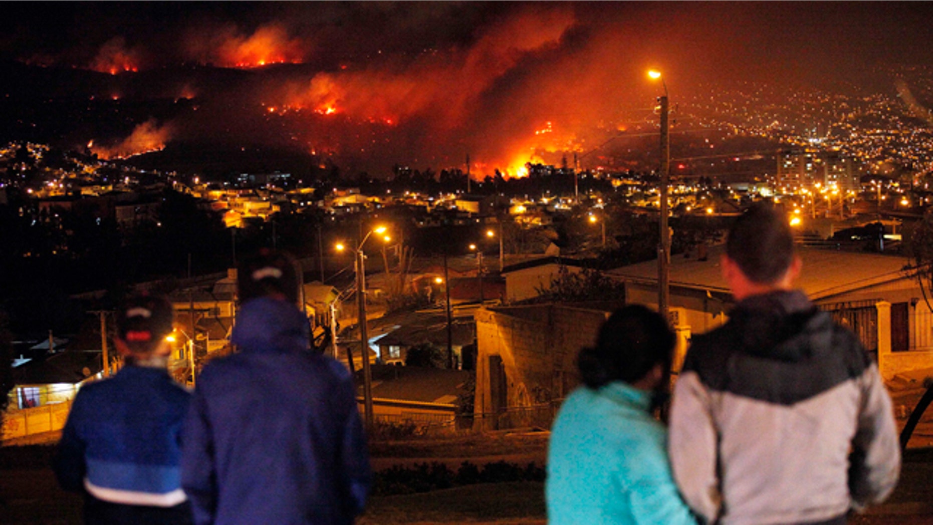 April 13, 2014: People watch as a forest fire rages towards urban areas in the city of Valparaiso, Chile. Authorities say the first fire has destroyed at least 500 homes and is forcing evacuations. ( AP Photo/ Luis Hidalgo)