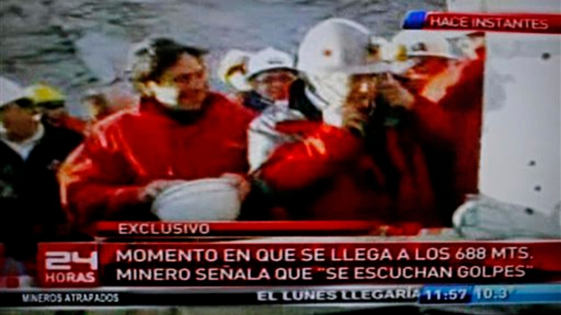 In this frame grab from TV channel 24 Horas, Chile's Mining Minister Laurence Golborne, left, smiles as an unidentified official listens with a medical oscilloscope to unknown sounds coming from the area of a collapsed mine where about 33 miners have been trapped for 17 days in Copiapo, Chile, Sunday, Aug. 22, 2010. The miners have been trapped below the surface since the main access collapsed on Aug. 5 due to tons of falling rock. The text at bottom reads in Spanish "Moment that it (a drill) reaches 688 meters. Miner indicates that 'knocking is heard'." (AP Photo)