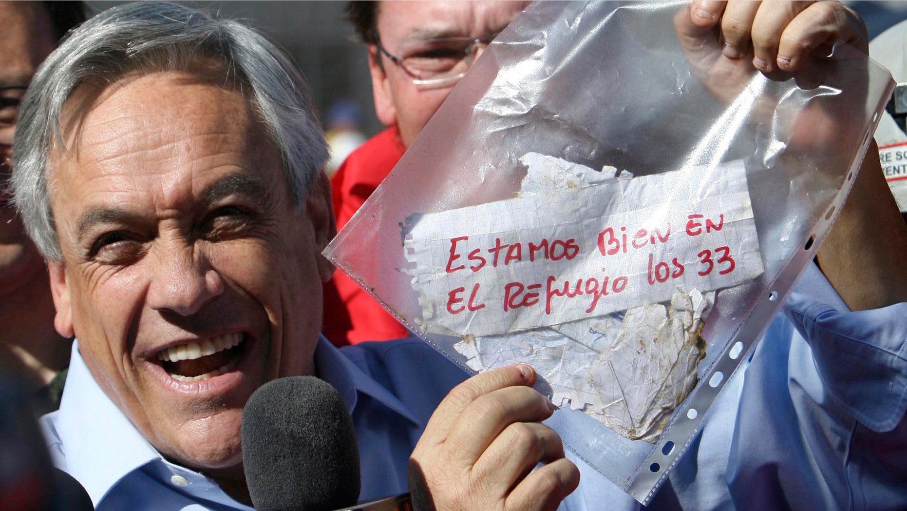 President Sebastian Pinera holds up a plastic bag containing a message,from miners trapped in a collapsed mine that reads in Spanish "We are ok in the refuge, the 33 miners" in Copiapo, Chile. (AP Photo/Hector Retamal, File)
