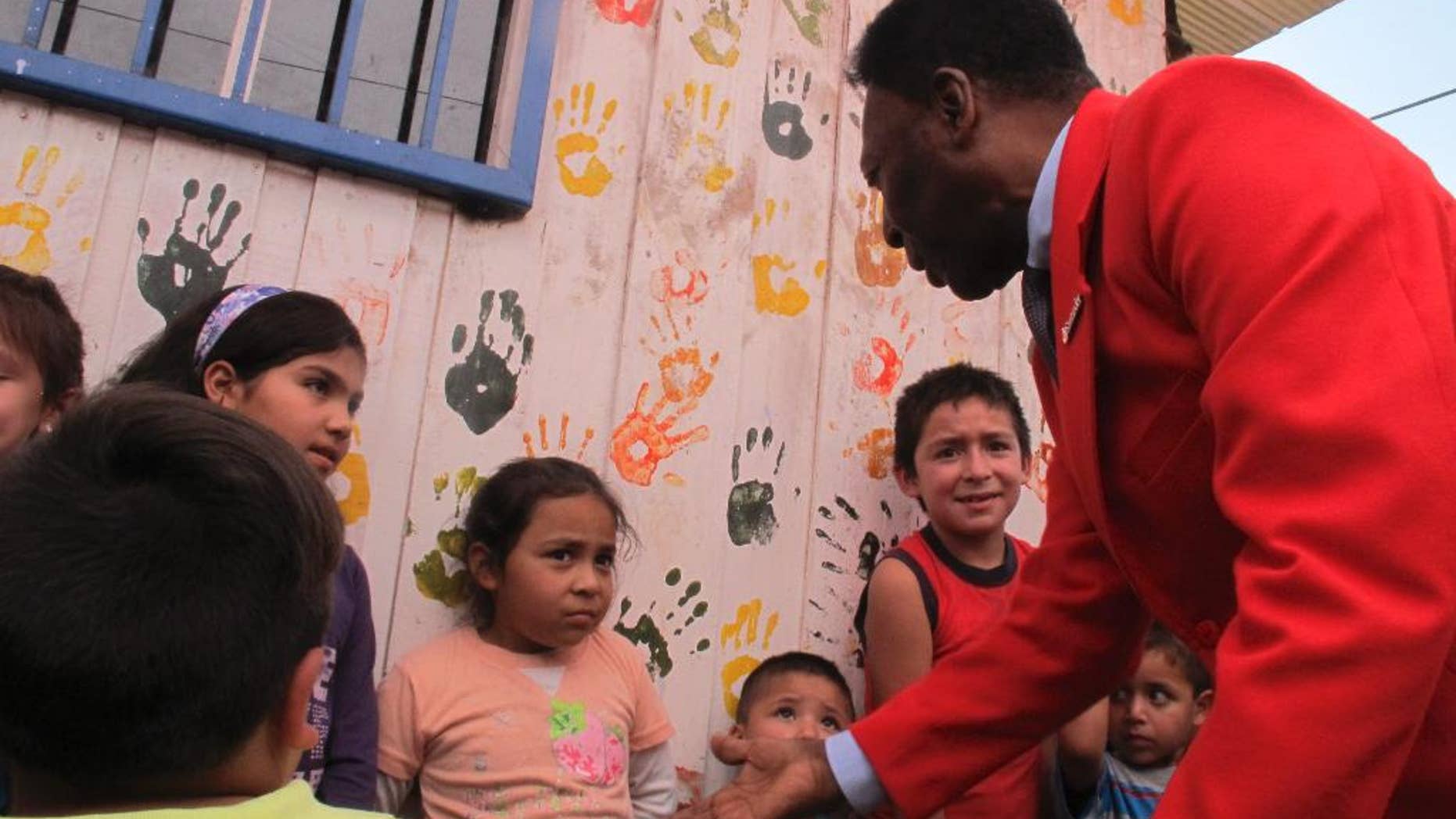 Brazilian soccer legend Pele puts out his hand, while greeting children in a visit to a slum in Santiago, Chile, Thursday, April 9, 2015. The activity was organized Thursday by a local NGO and a bank, seeking to inspire Chilean children. Pele says he has "happily recovered" from a recent health scare. (AP Photo/Luis Andres Henao)