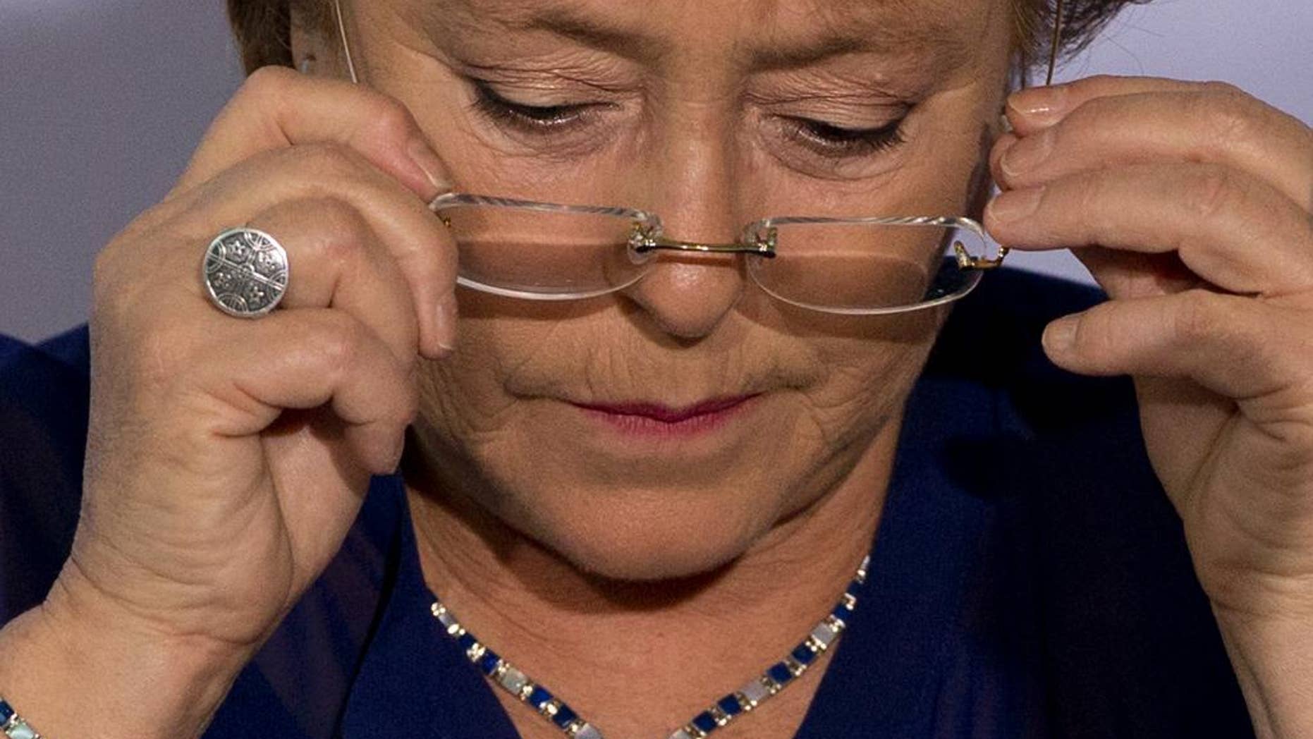 FILE - In this Dec. 9, 2014, file photo, Chile's President Michelle Bachelet puts on her glasses during an event to announce a new economic report on Latin America at the 2014 Iberoamerican Summit in Veracruz, Mexico. President Bachelet came under fire on Wednesday Feb. 11, 2015, over complaints her family got privileged access to a bank loan for a land deal. Chile’s Que Pasa magazine reported that a company half-owned by Bachelet’s daughter-in-law, Natalia Compagnon, received a $10 million loan from Banco de Chile. (AP Photo/Rebecca Blackwell, File)
