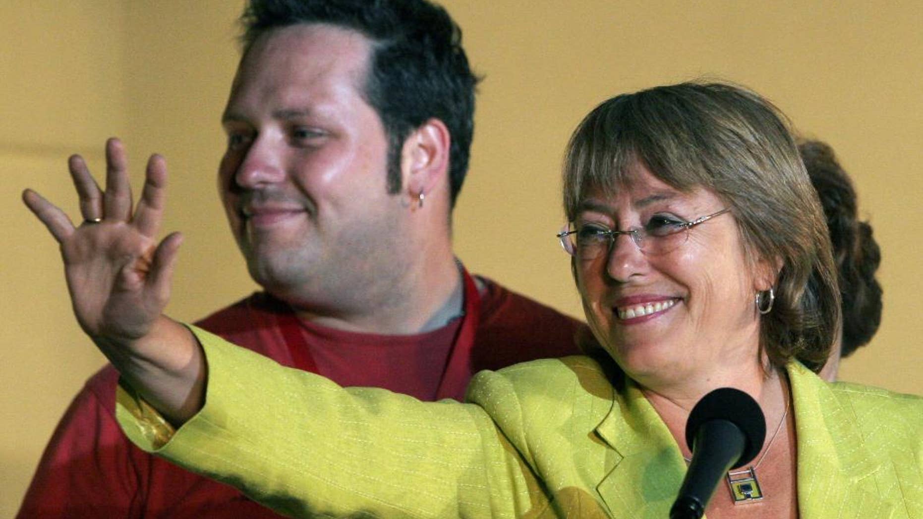 FILE - In this Dec. 11, 2005 file photo, Chile's presidential candidate Michelle Bachelet waves to supporters as her son Sebastian Davalos stands behind in Santiago, Chile. Chilean opposition lawmakers are asking for a full investigation to determine whether Bachelet's son got privileged access to a bank loan. Lawmakers demanded the probe on Monday, Feb. 16, 2015, saying Davalos and his wife benefited from privileged information and treatment in receiving a $10 million loan to buy land that was later sold for about $15 million. The loan was approved a day after Bachelet was elected president in Dec. 2013 for her second term. (AP Photo/Jorge Saenz, File)