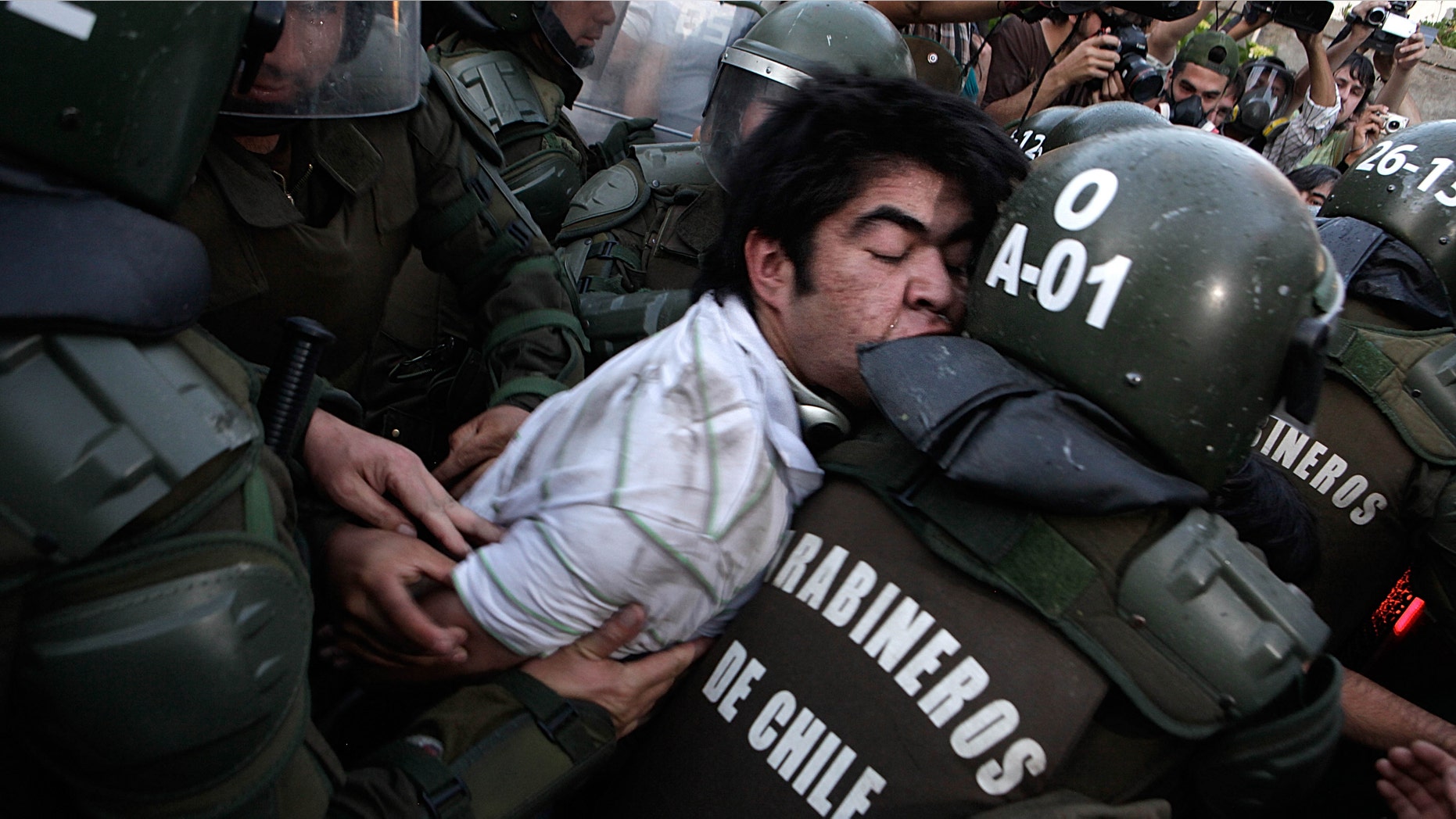 Police officers detain a human rights activist after clashes during an event honoring Miguel Krassnoff, a former Chilean army brigadier during the 1973-1990 dictatorship of August Pinochet, in Santiago, Chile, Monday, Nov. 21, 2011. Krassnoff is currently serving a 144-year sentence for homicide and forced disappearances. (AP Photo/Luis Hidalgo)