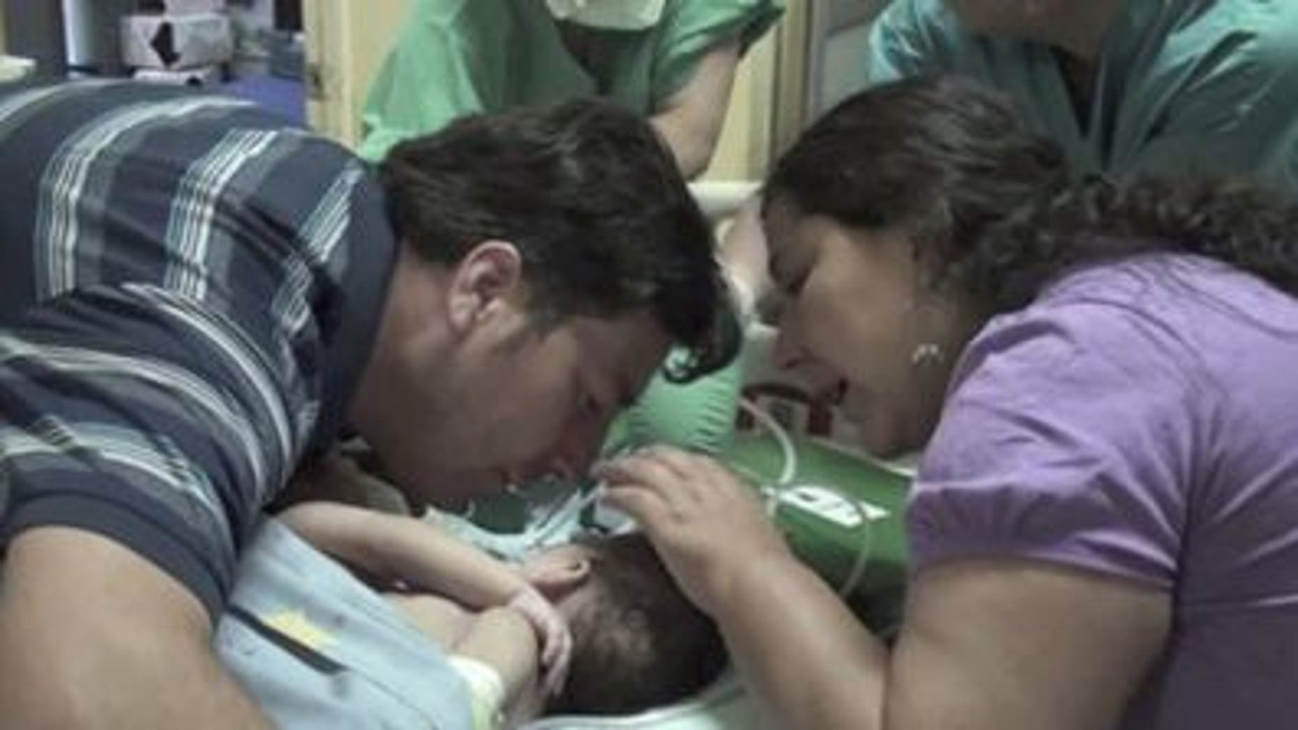 December 13, 2011: In this image taken from a video released by Luis Calvo Mackenna hospital, Jessica Navarrete, right, and Roberto Paredes, parents of conjoined twins Maria Paz and Maria Jose Paredes Navarrete kiss them before a separation surgery in Santiago, Chile.