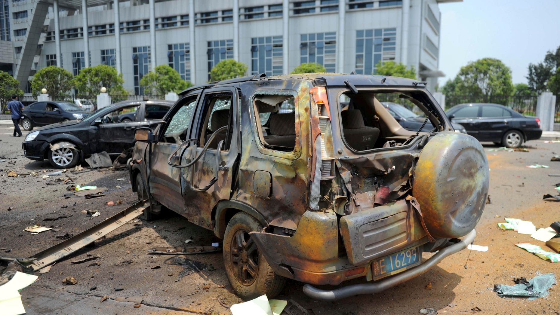 A damaged vehicle sits at the site of an explosion near the Linchuan district government building in Fuzhou city, east China's Jiangxi Province. Hours after homemade bombs blasted government buildings, some Chinese were quick to glorify the disgruntled bomb-setter _ a sign of the bitterness many feel toward the government for chasing growth while neglecting justice.