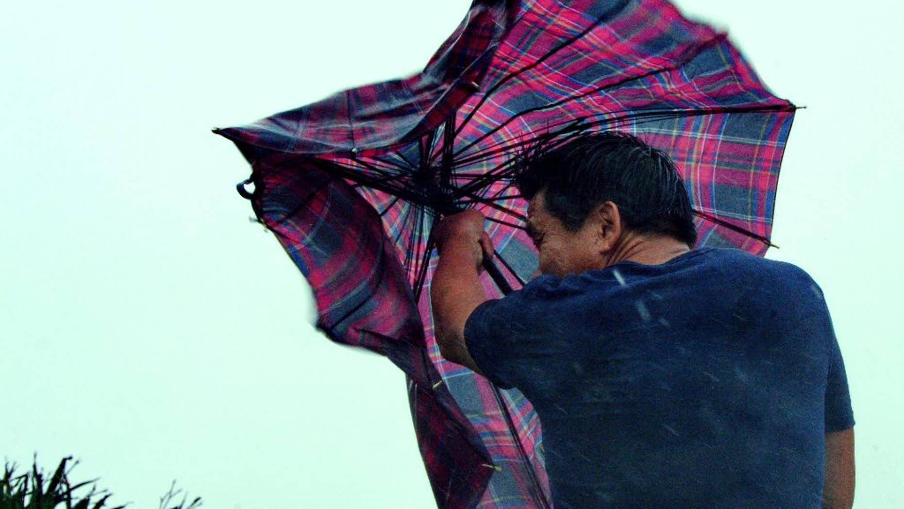In this Aug. 8, 2015 photo provided by China's Xinhua News Agency, a man walks against gale in Shishi, southeast China's Fujian Province. Typhoon Soudelor hit the city of Putian in Fujian province late Saturday night and weakened into a tropical storm as it moved across the province. The Fujian Civil Affairs Department said that it collapsed 36 houses and damaged 281 others. (Zhang Guojun/Xinhua News Agency via AP) NO SALES