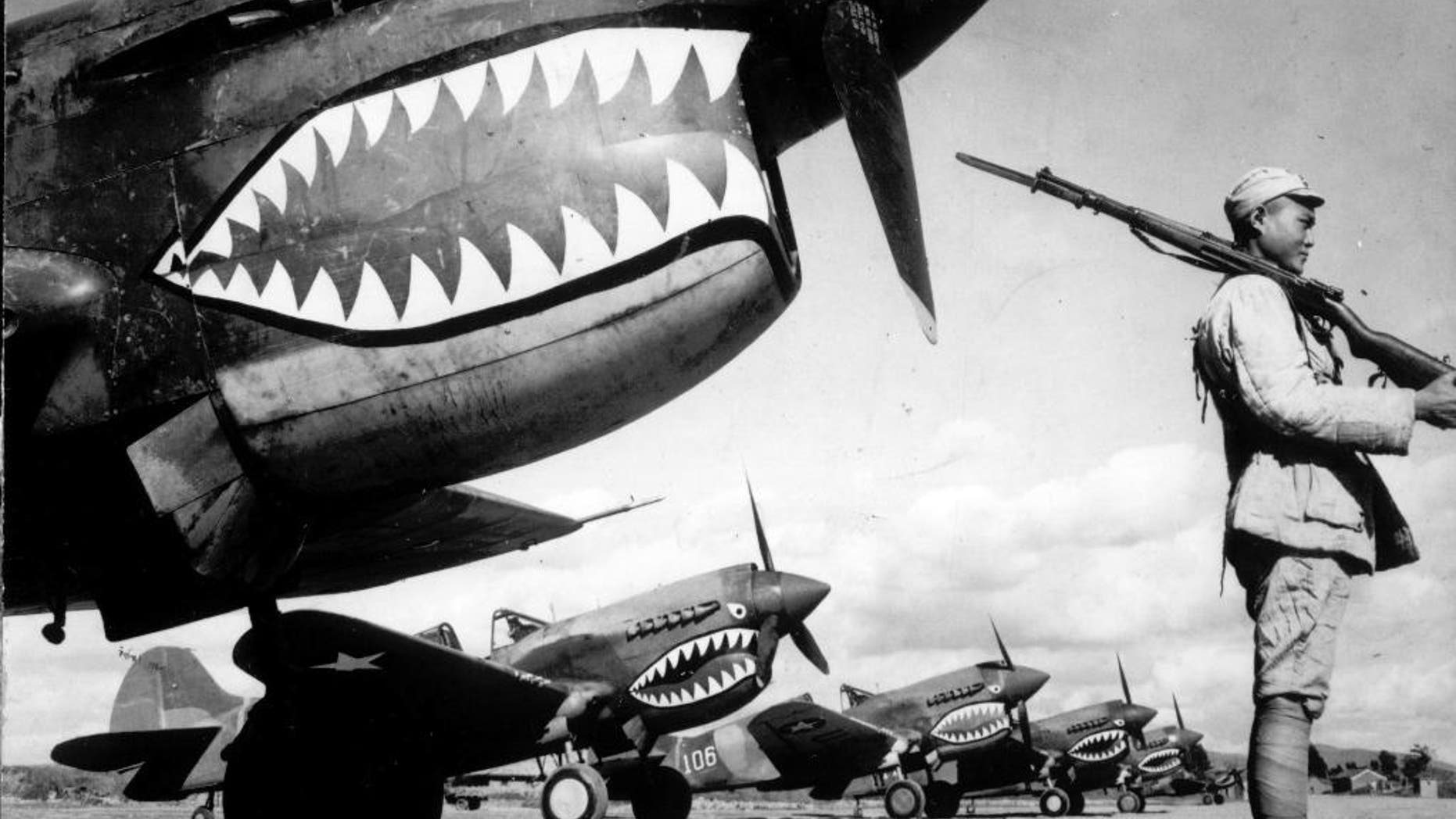 In this 1943 photo, guarded by a Chinese soldier, a squadron of Curtiss P-40 fighter planes, decorated with the typical shark face of the famed Flying Tigers, are lined up at an unknown airbase in China. An airfield in southern China from which the famed Flying Tigers took off to fight Japanese warplanes is being converted to battle a new enemy: drought. (AP Photo)