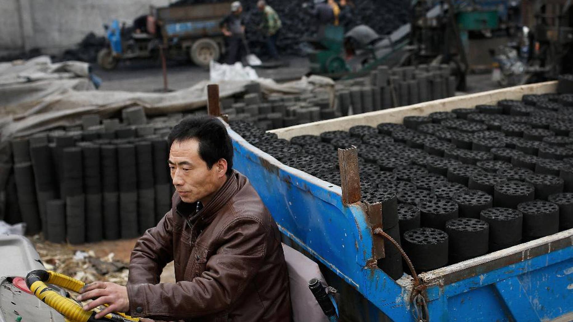 In this Nov. 27, 2014 photo, a man drives his tricycle cart loaded with coal briquettes as he leaves a coal process station in Tangxian in China's Hebei province. Coal production in China, the world's biggest coal-consuming nation, fell by 6 percent in the first four months of the year 2015 as the economy slows and the government makes a concerted push to reduce carbon emissions. The National Development and Reform Commission said Tuesday, May 26, 2015 that Chinese imports of coal also fell, plummeting 38 percent. (AP Photo/Andy Wong)