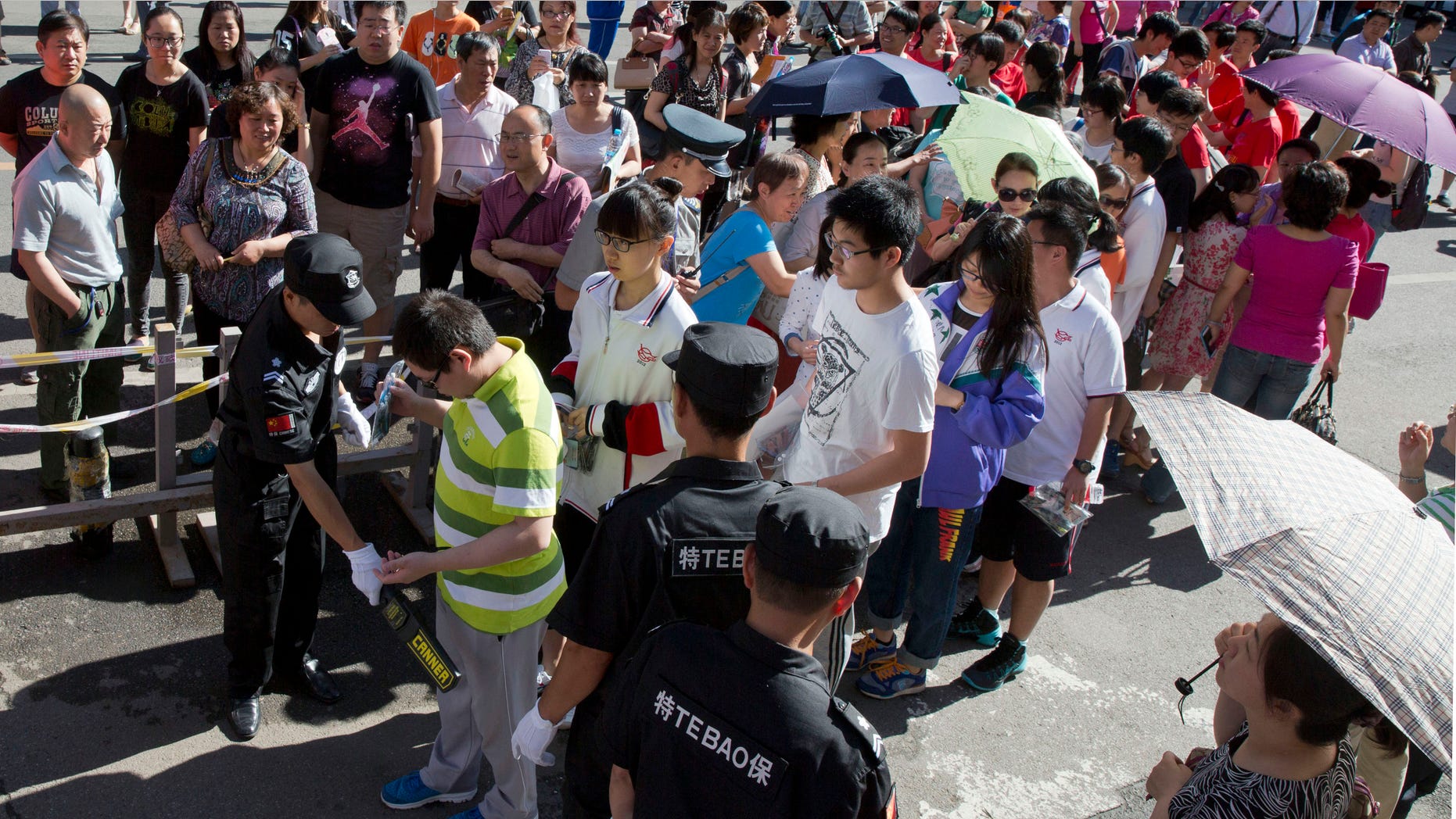 June 7, 2015 - A security guard uses a metal detector to check students arriving for the annual Gao Kao or national college entrance exam held at a school in Beijing. More than 9 million Chinese students will compete in the 2-day exams for around 7 million seats in the nation's colleges.