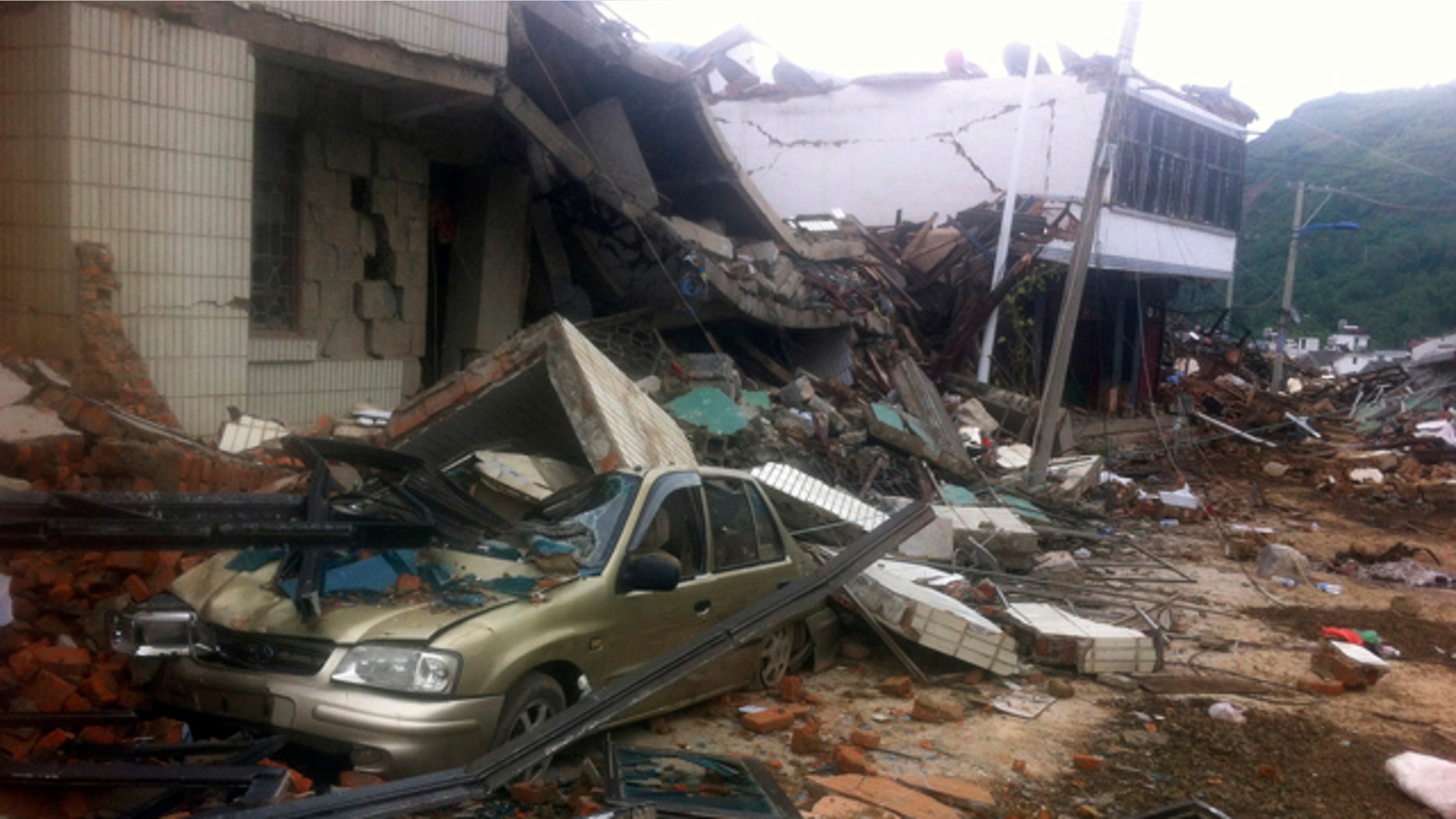 August 4, 2014: A car sits crushed by a collapsed building at the epicenter of an earthquake that struck the town of Longtoushan on Sunday, in Ludian County in southwest China's Yunnan Province. (AP Photo)