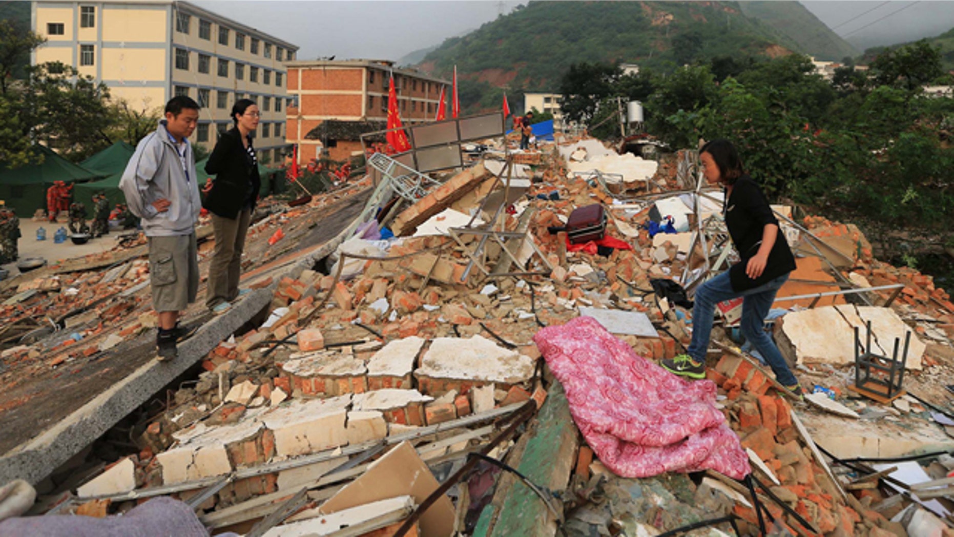 August 5, 2014: In this photo provided by China's Xinhua News Agency, teachers search for their belongings from collapsed dormitories at Longquan Middle School in Longtoushan town of Ludian county, southwest China's Yunnan Province. (AP Photo/Xinhua, Xing Guangli)