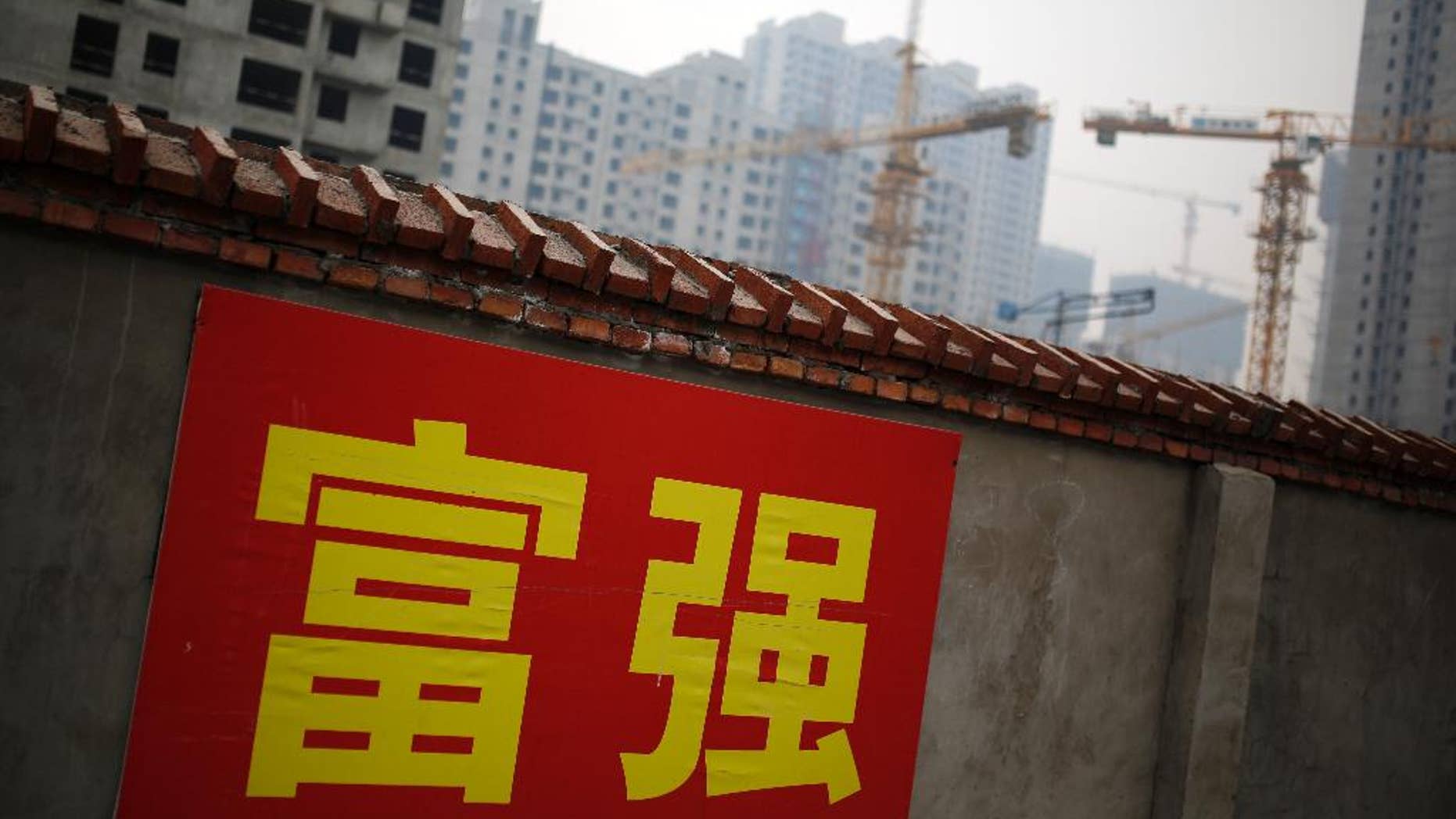 FILE - In this Dec. 9, 2014 file photo, Chinese government propaganda words which read "Prosperity and Powerful" are displayed on a wall near a construction site in Beijing, China. China's economic growth slowed to 7.4 percent last year, the weakest expansion in more than two decades. The numbers released Tuesday, Jan. 20, 2014 are still miles ahead of growth rates in major industrialized economies, but represent a sharp decline from double digit growth in previous years. That adds to pressure on the country's communist leaders as they try to prevent a sharper slowdown in 2015 while overhauling the economy.(AP Photo/Andy Wong, FIle)
