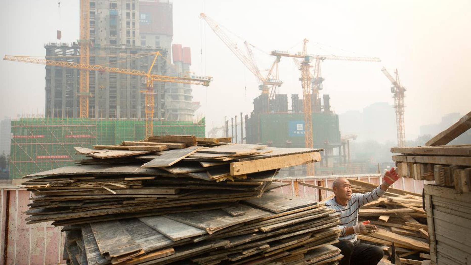 FILE - In this Oct. 6, 2015 file photo, a worker tosses boards onto the back of a truck at a construction site in Beijing. China’s official data show economic growth slowing but skeptics say the downturn is much deeper than Beijing admits. The latest data Tuesday, Oct. 20, 2015, showed growth in the world’s No. 2 economy fell to a six-year low of 6.9 percent in the latest quarter. Private sector economists, however, say this year’s true rate might be as low as 4 percent.(AP Photo/Mark Schiefelbein, File)