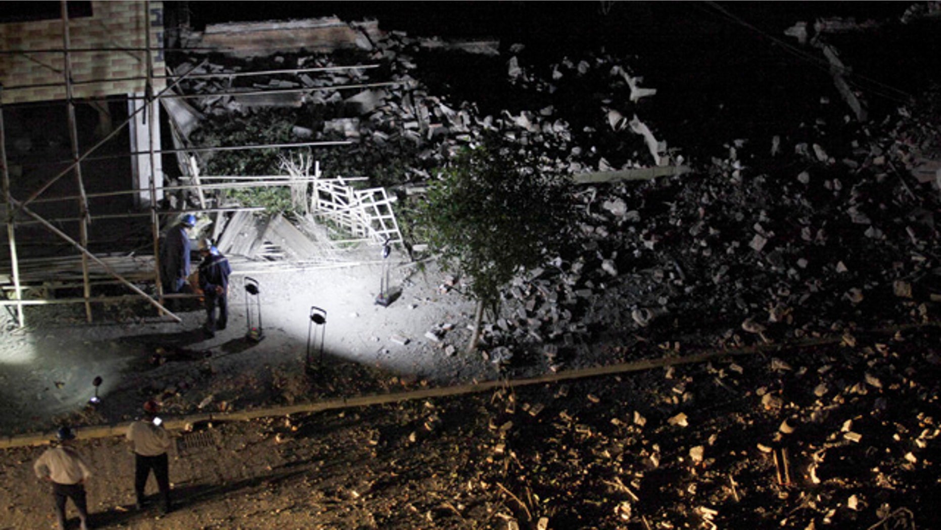 Sept. 30, 2015: Men gather near the site of a residential building which partially collapsed by what police are describing as explosive devices delivered in mail packages in Liucheng county in south China's Guangxi Zhuang Autonomous Region. (Chinatopix Via AP)