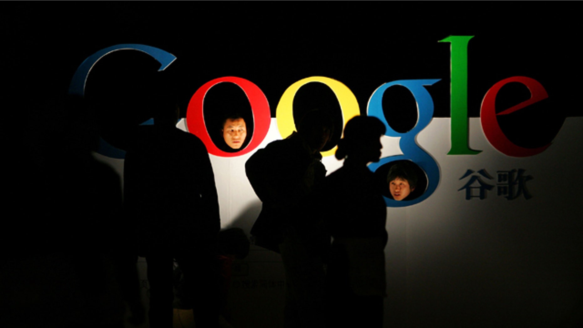 Chinese poke their heads through a Google logo shortly after Google debuts its Chinese Language brand name in the Beijing Hotel in Beijing. Google Inc. said Wednesday that its search engine has been partially blocked in the country.