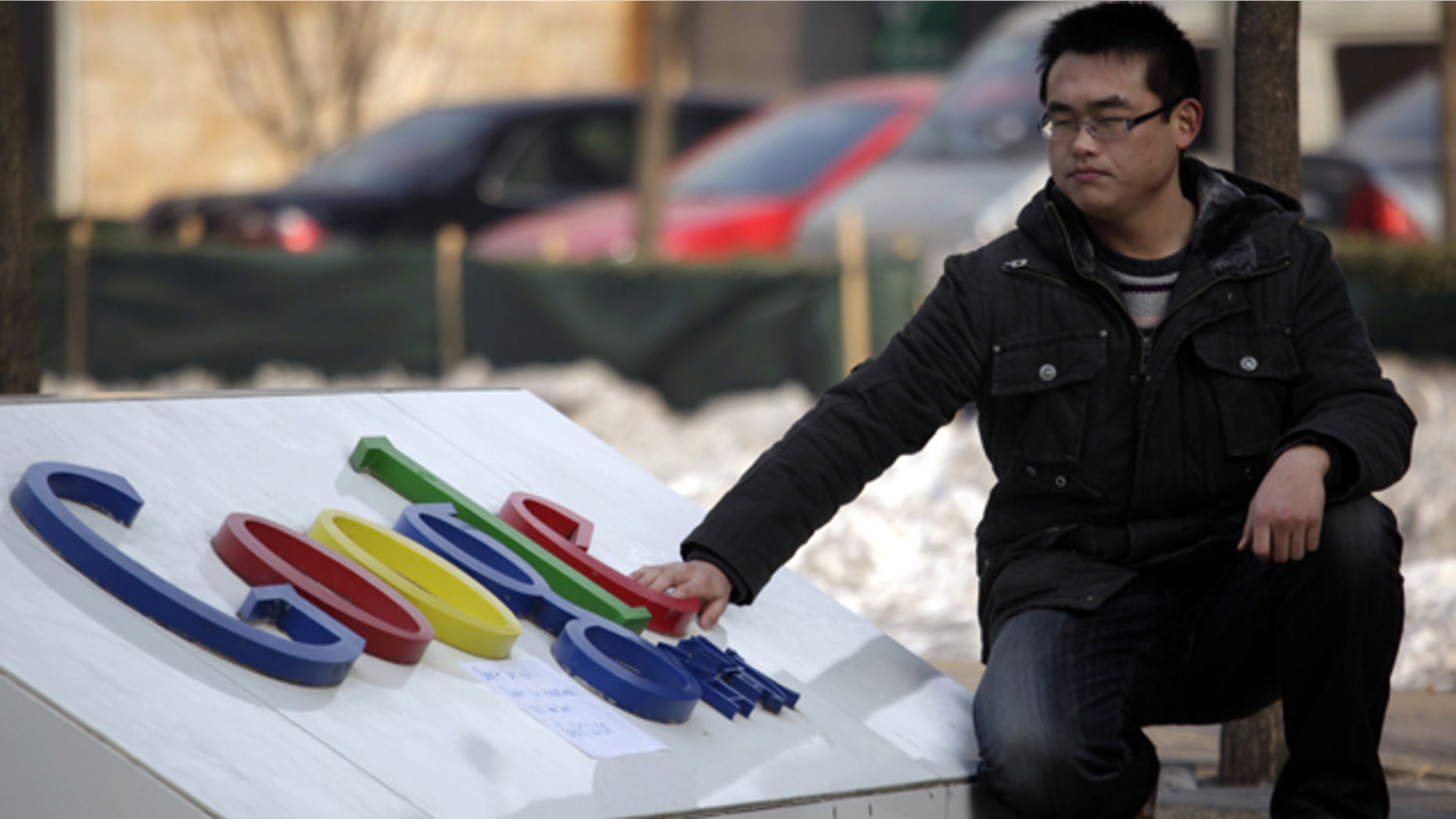 A Chinese man shuts his eyes briefly as he places a hand on the Google logo outside the Google China headquarters in Beijing.