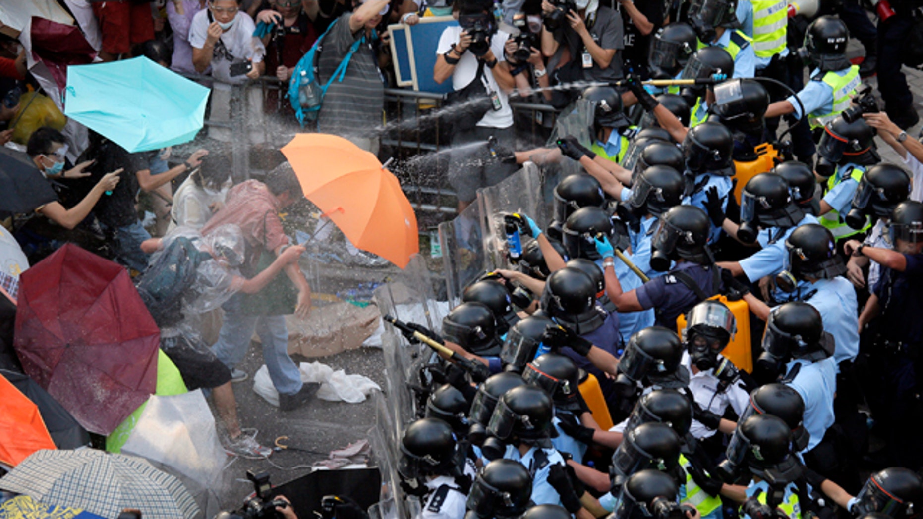 FILE - In this Sept. 28, 2014 file photo, riot police use pepper spray against protesters after thousands of people block a main road to the financial central district outside the government headquarters in Hong Kong. (AP Photo/Vincent Yu, File)