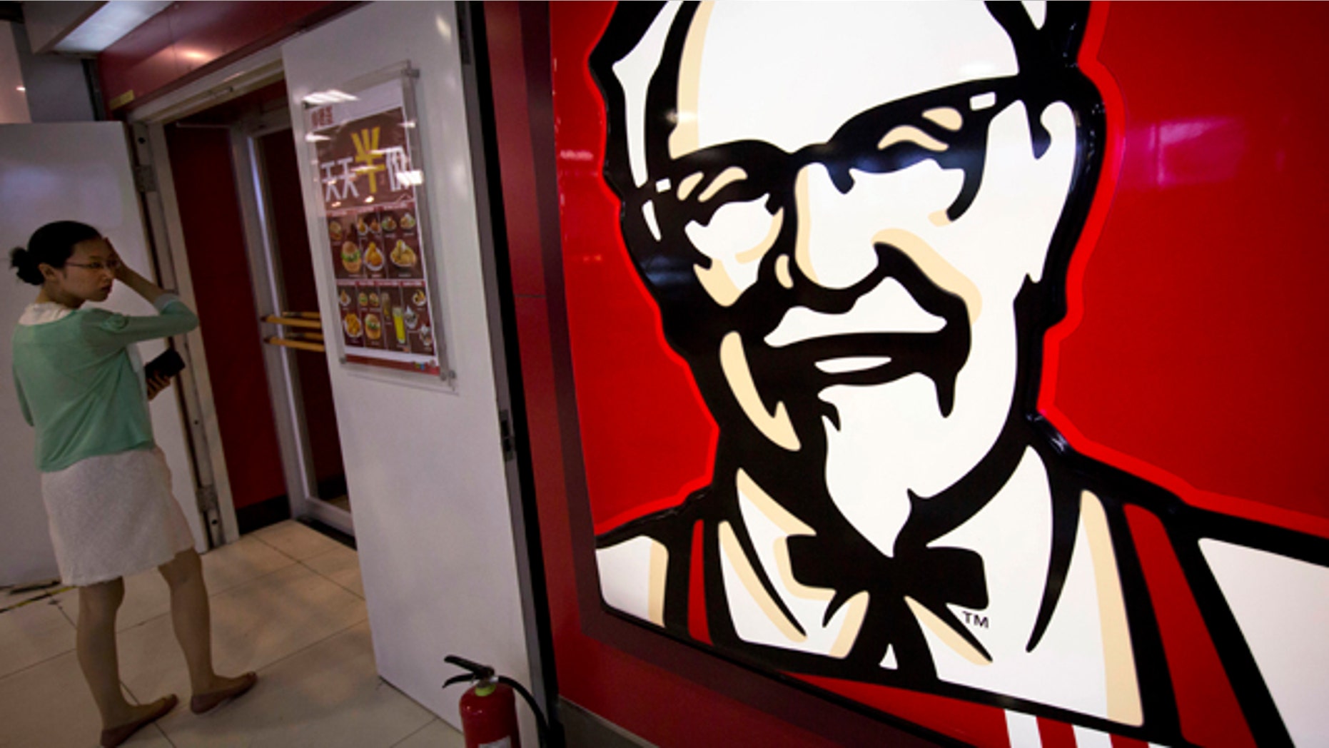 FILE - In this July 31, 2014 photo, a woman looks at a menu with words 'everyday half-price' in front of a KFC fast food restaurant in Beijing, China. (AP Photo/Andy Wong, File)